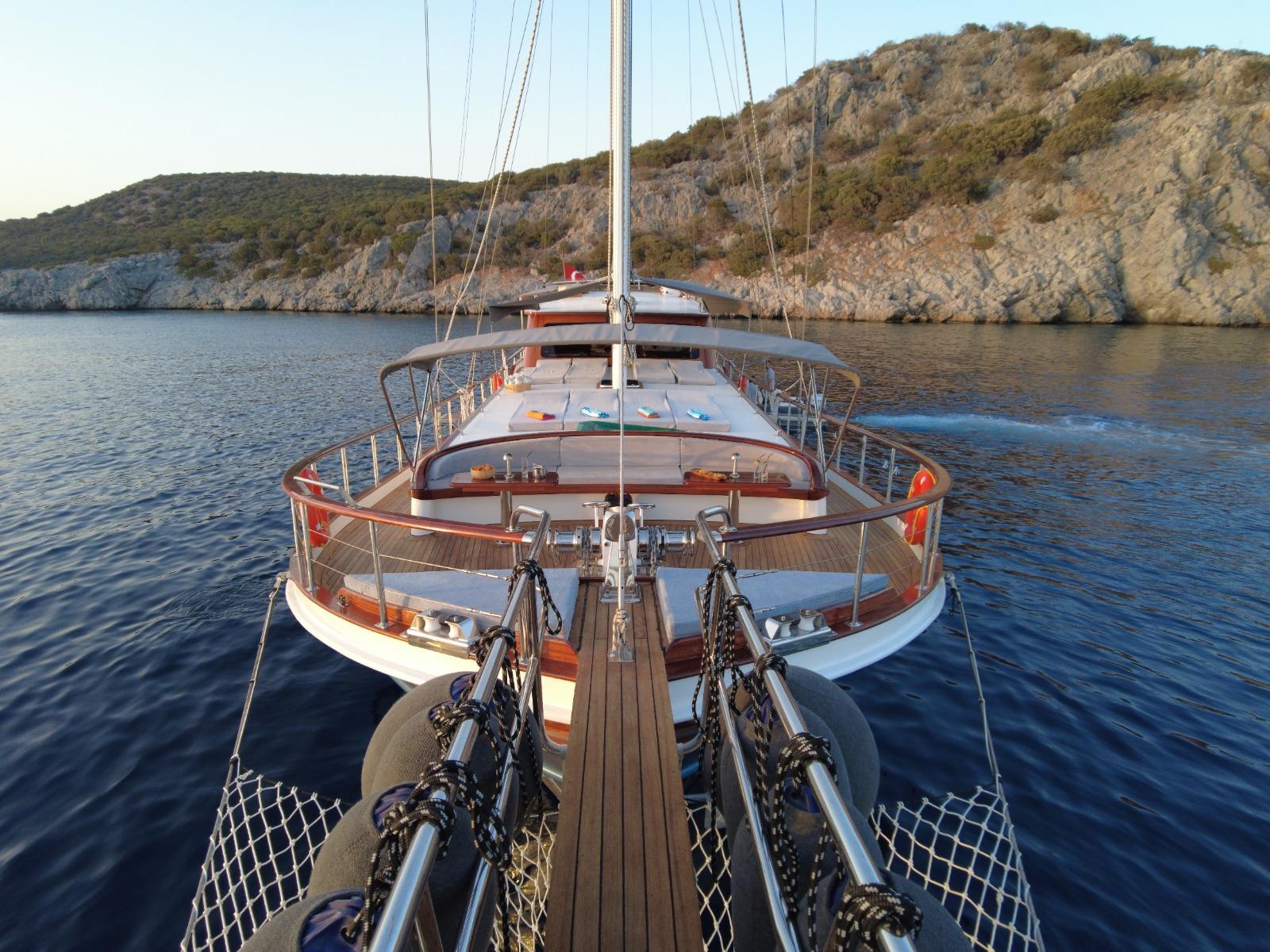 gulet bow deck with wooden planking, anchor chain, rigging and mast in secluded bay