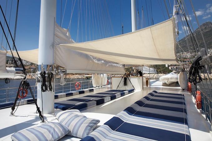 gulet bow deck with blue and white striped cushions under cream shade sail