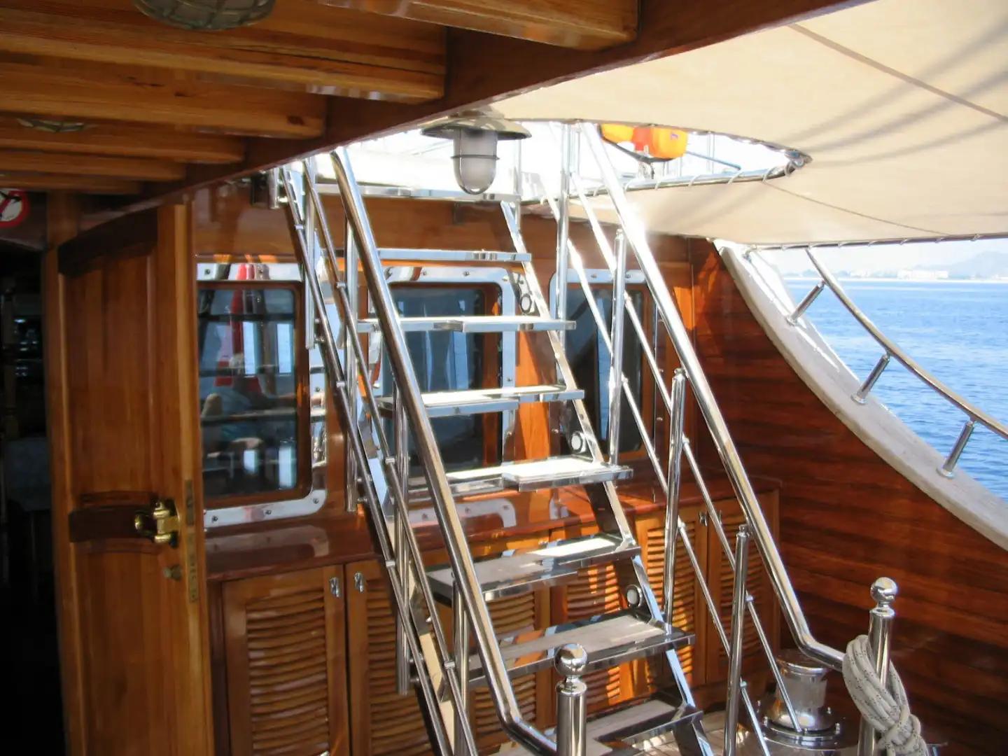 yacht interior staircase with polished stainless steel railings leading to upper deck