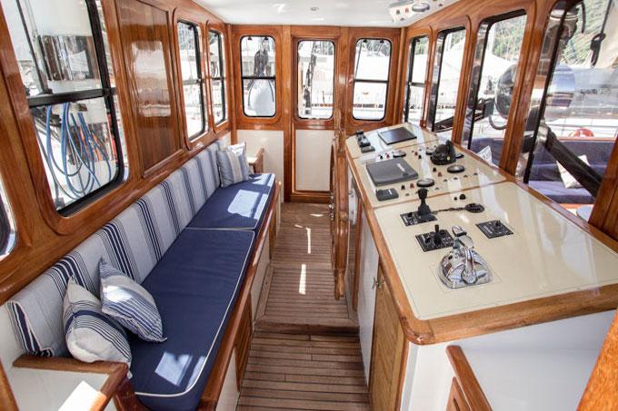 yacht wheelhouse interior with navigation console, helm station, and blue striped seating