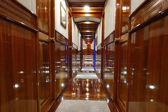 luxurious yacht corridor with glossy mahogany wood paneling and marble flooring leading to staircase