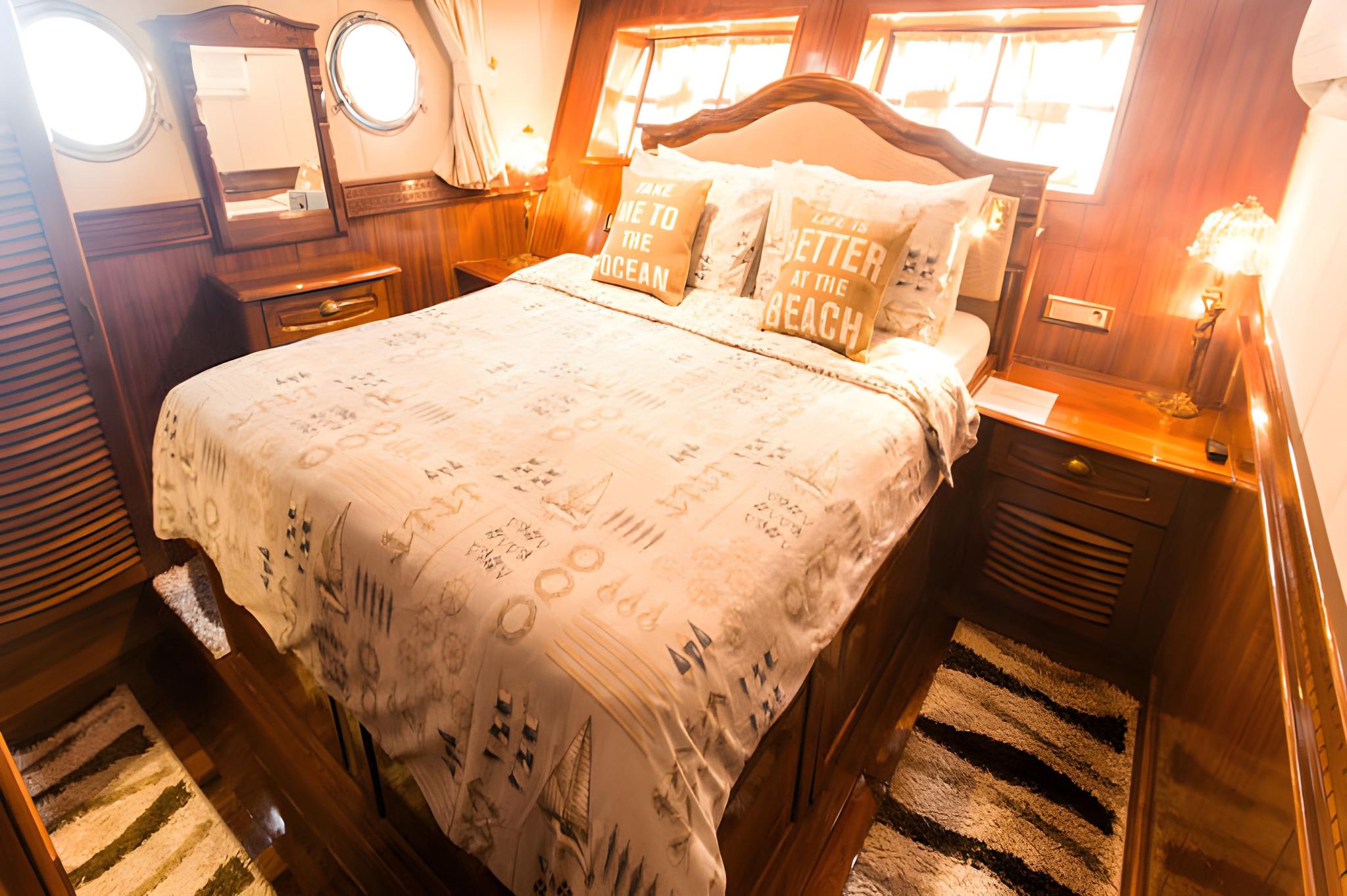 yacht guest cabin featuring double bed with patterned bedding and two circular portholes