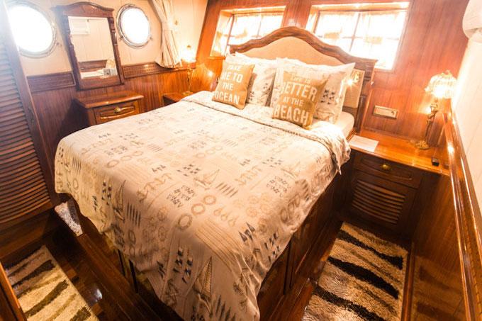 yacht guest cabin featuring double bed with patterned bedding and two circular portholes