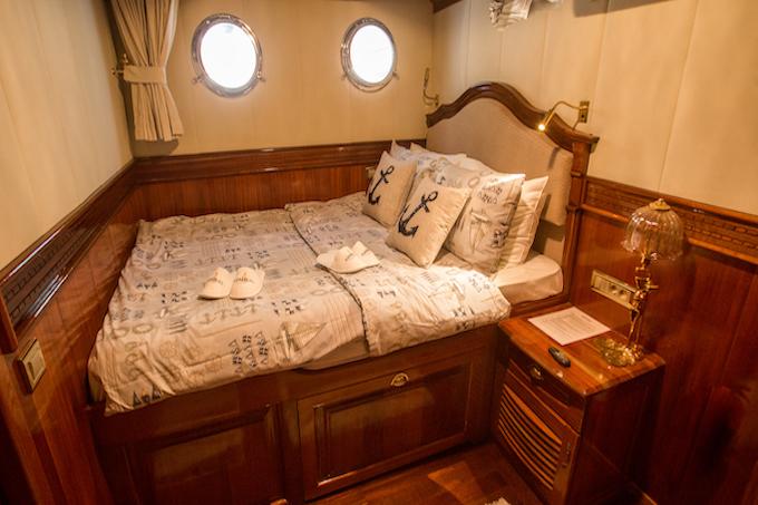 yacht guest cabin featuring double bed with nautical bedding and two round portholes