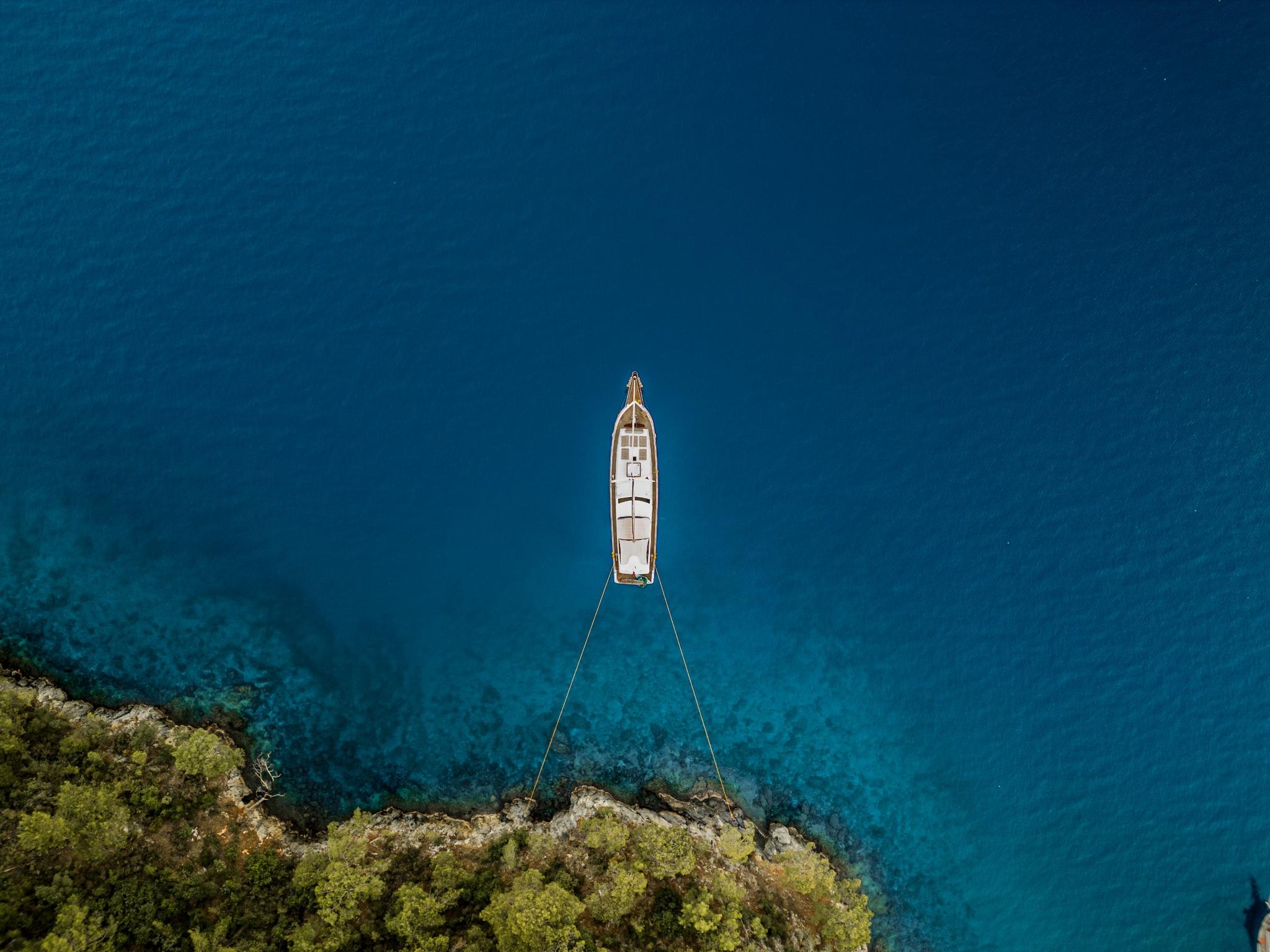 aerial view of white gulet yacht anchored in crystal clear turquoise Mediterranean waters