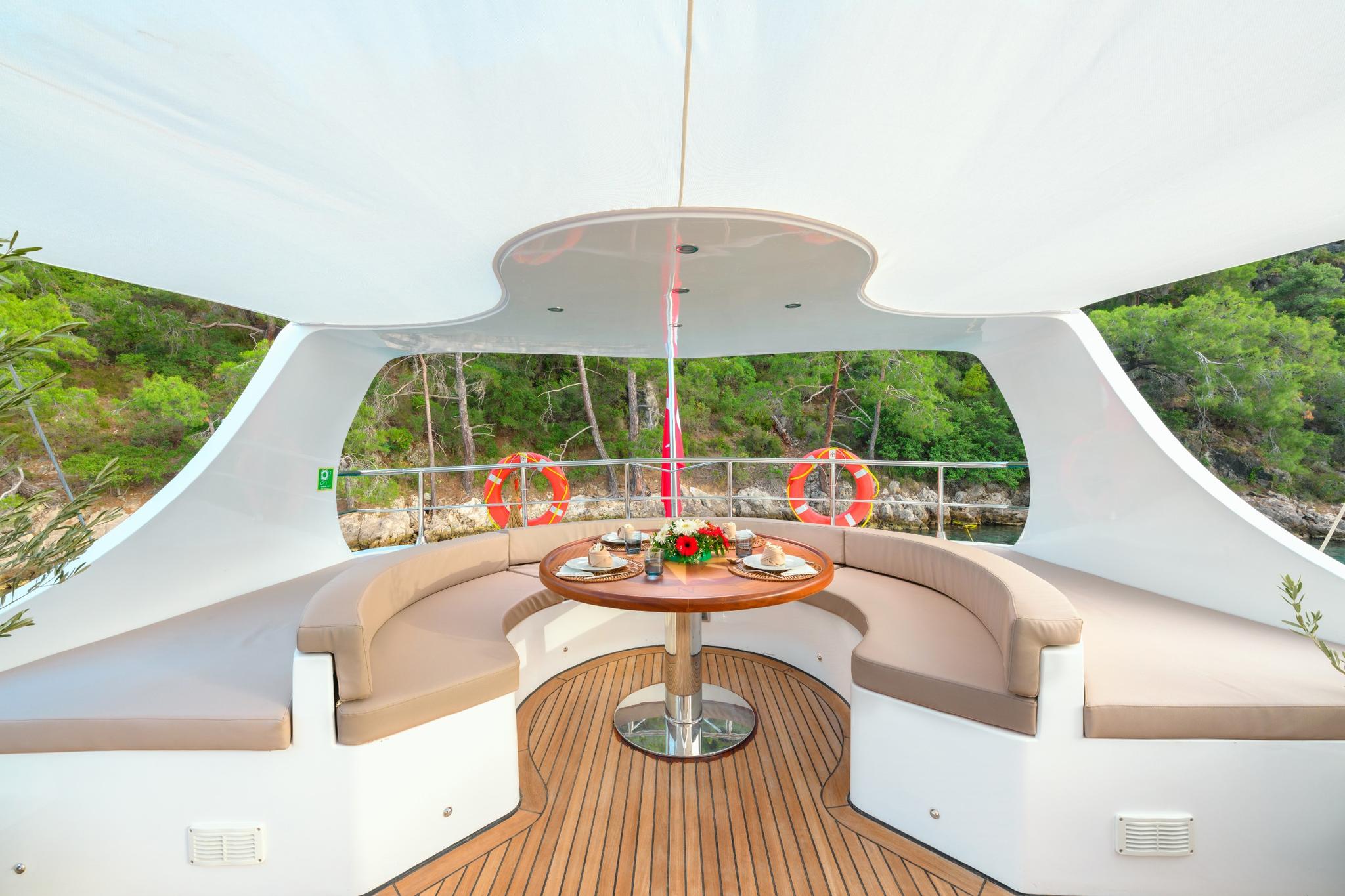 curved bench seating with round dining table on yacht's upper deck area