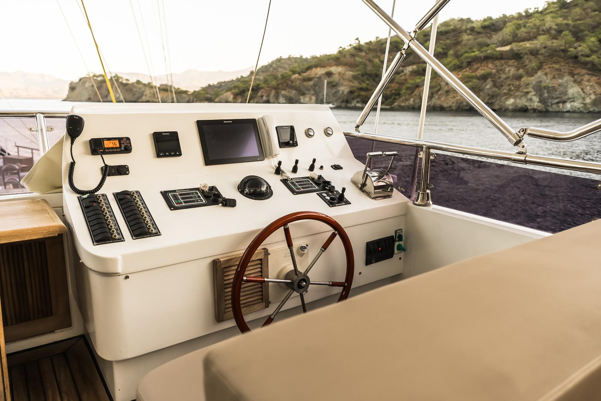 yacht helm station with multiple navigation displays, steering wheel and control panels in cockpit