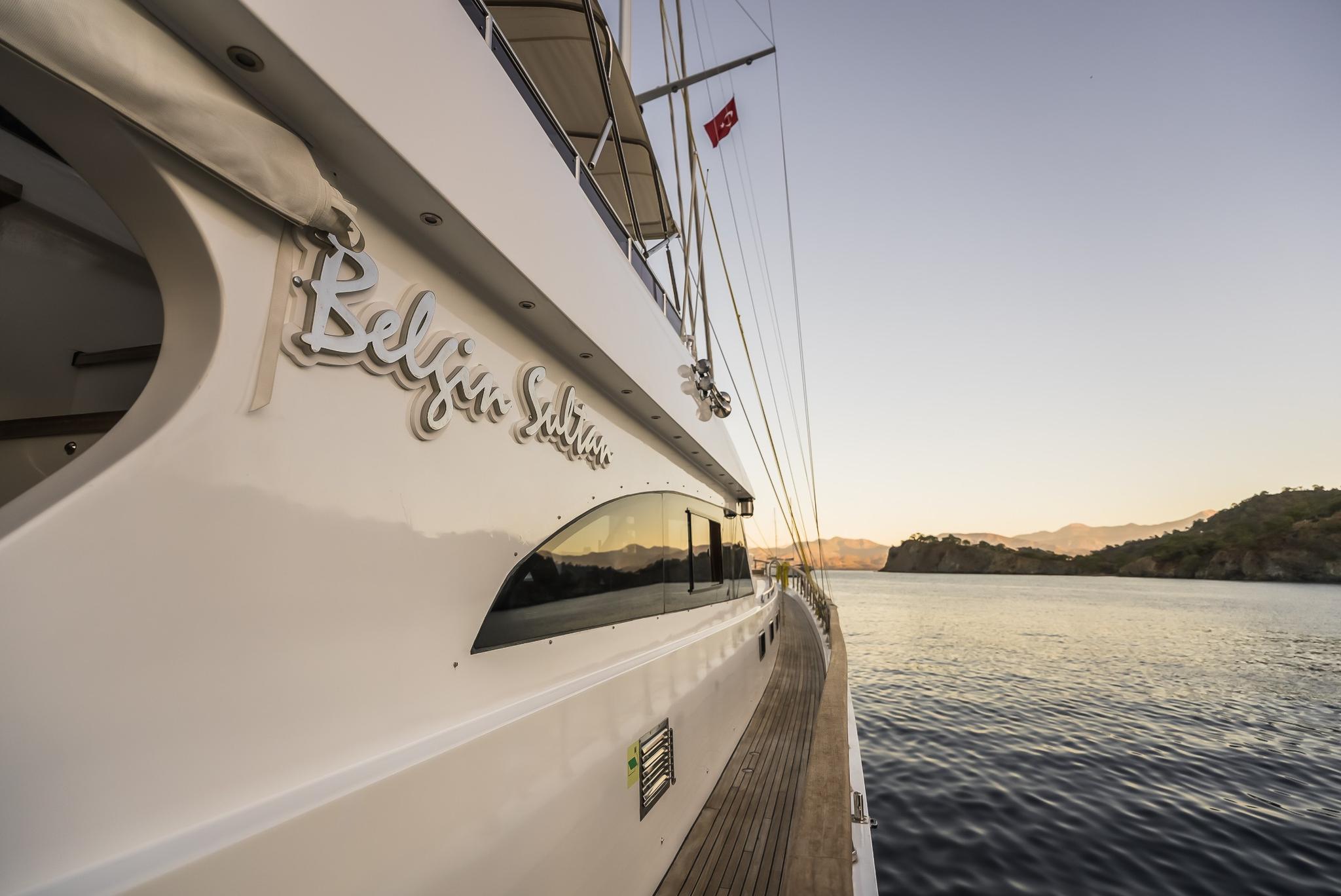 White luxury yacht side deck with teak decking and rigging at golden hour