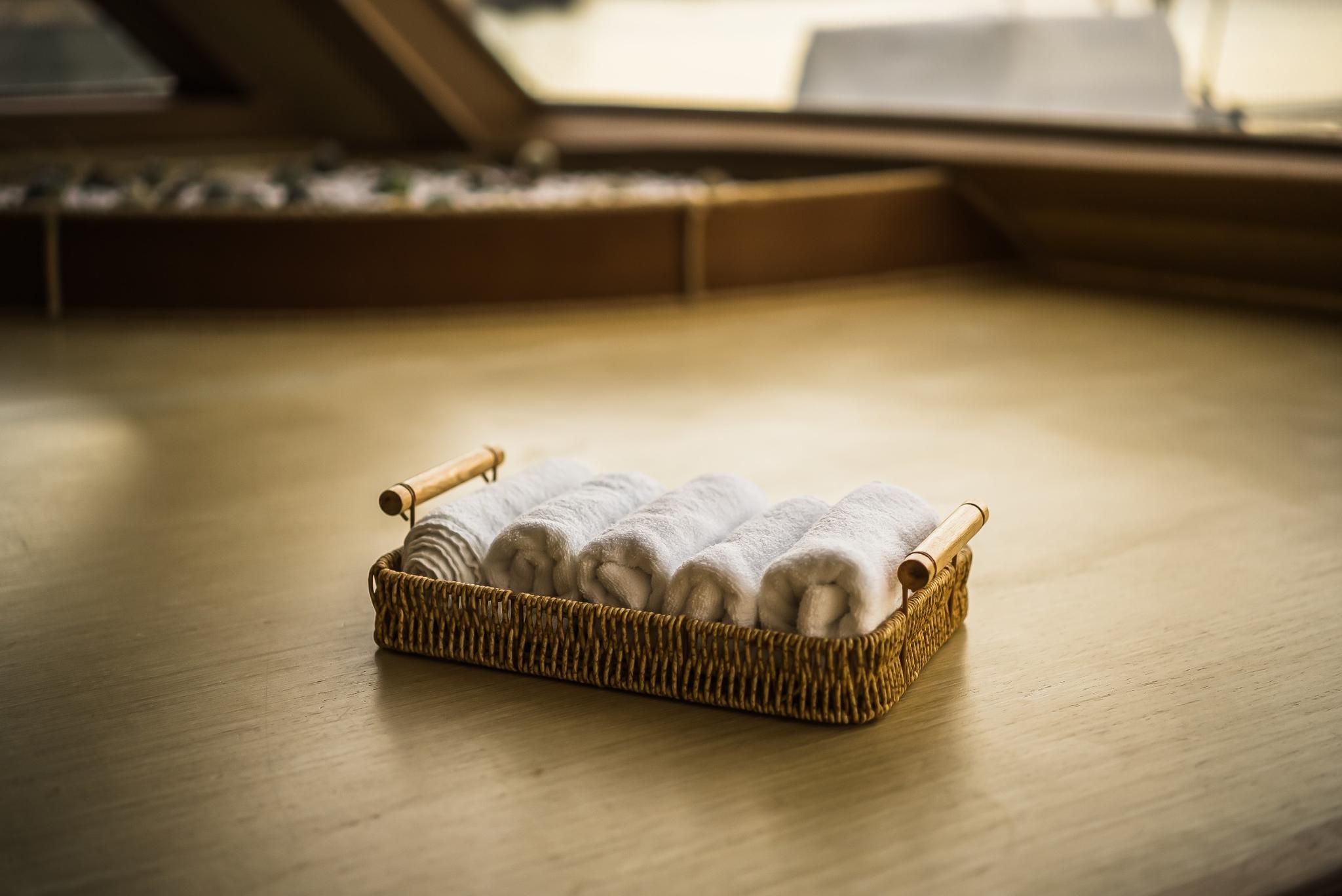 wicker towel basket with white rolled towels on wooden cabin floor
