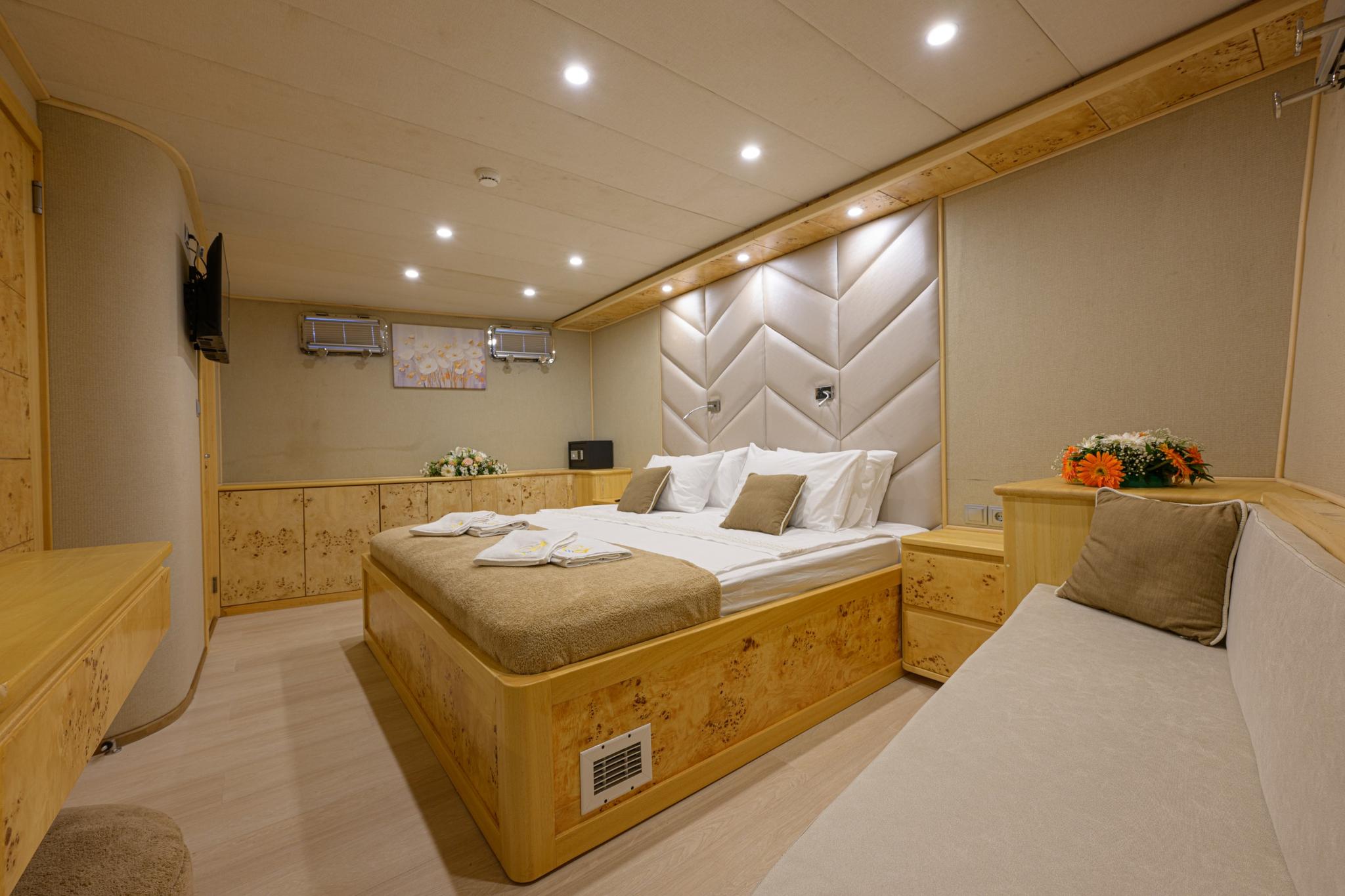 luxury yacht master cabin featuring diamond-pattern upholstered headboard, double bed with white linens, built-in furniture and seating area
