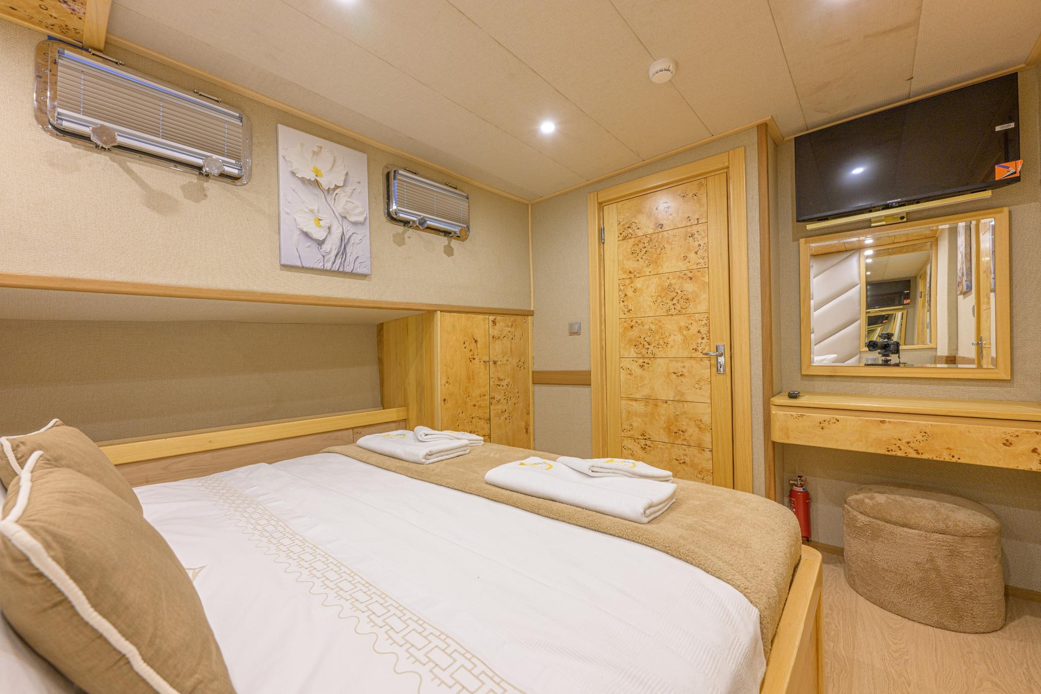 yacht guest cabin featuring double bed with beige linens and burr wood paneling