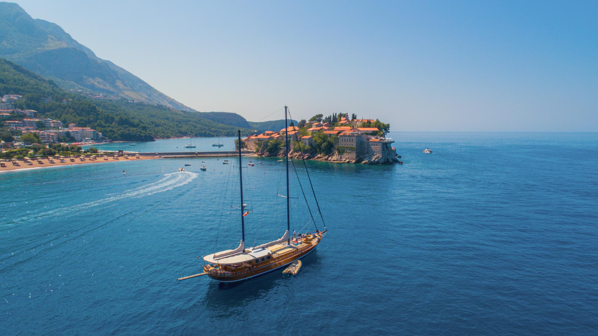 Aerial drone view of wooden gulet anchored off Sveti Stefan island Montenegro