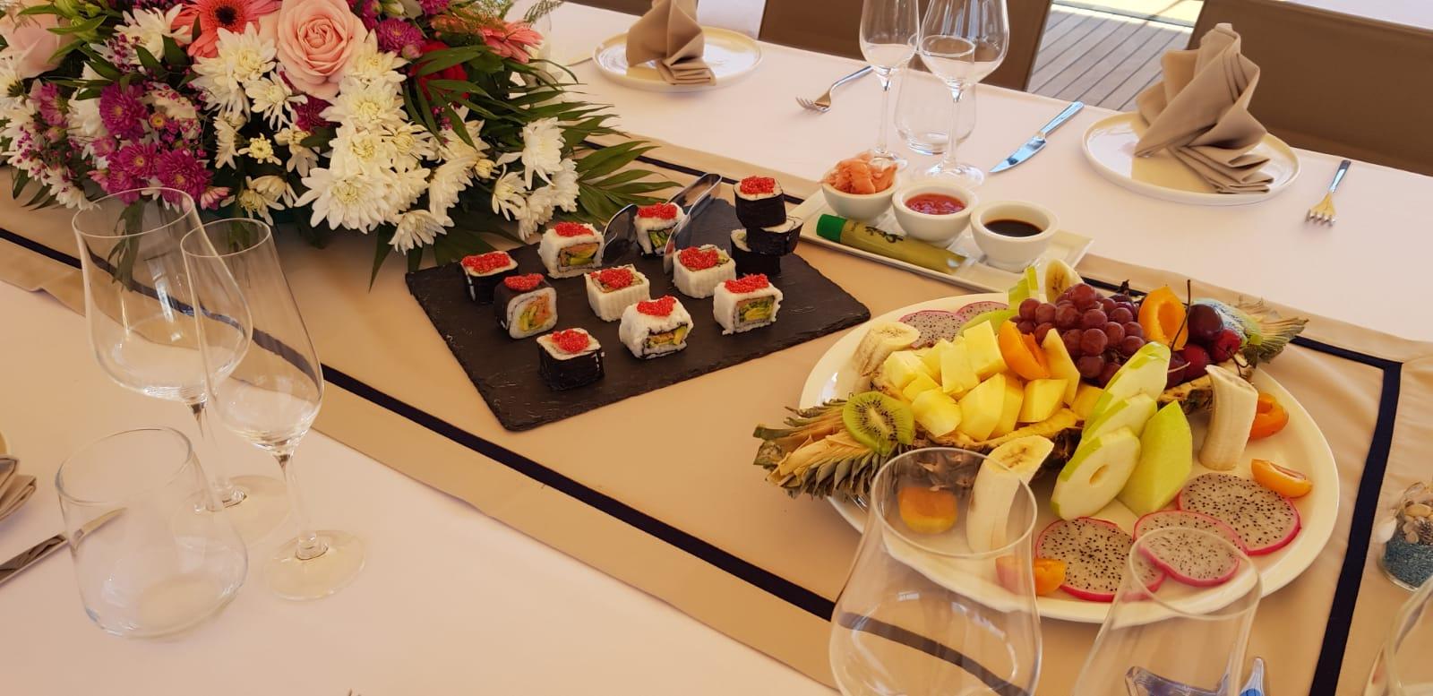 luxury yacht dining table set with sushi rolls on slate board and tropical fruit platter