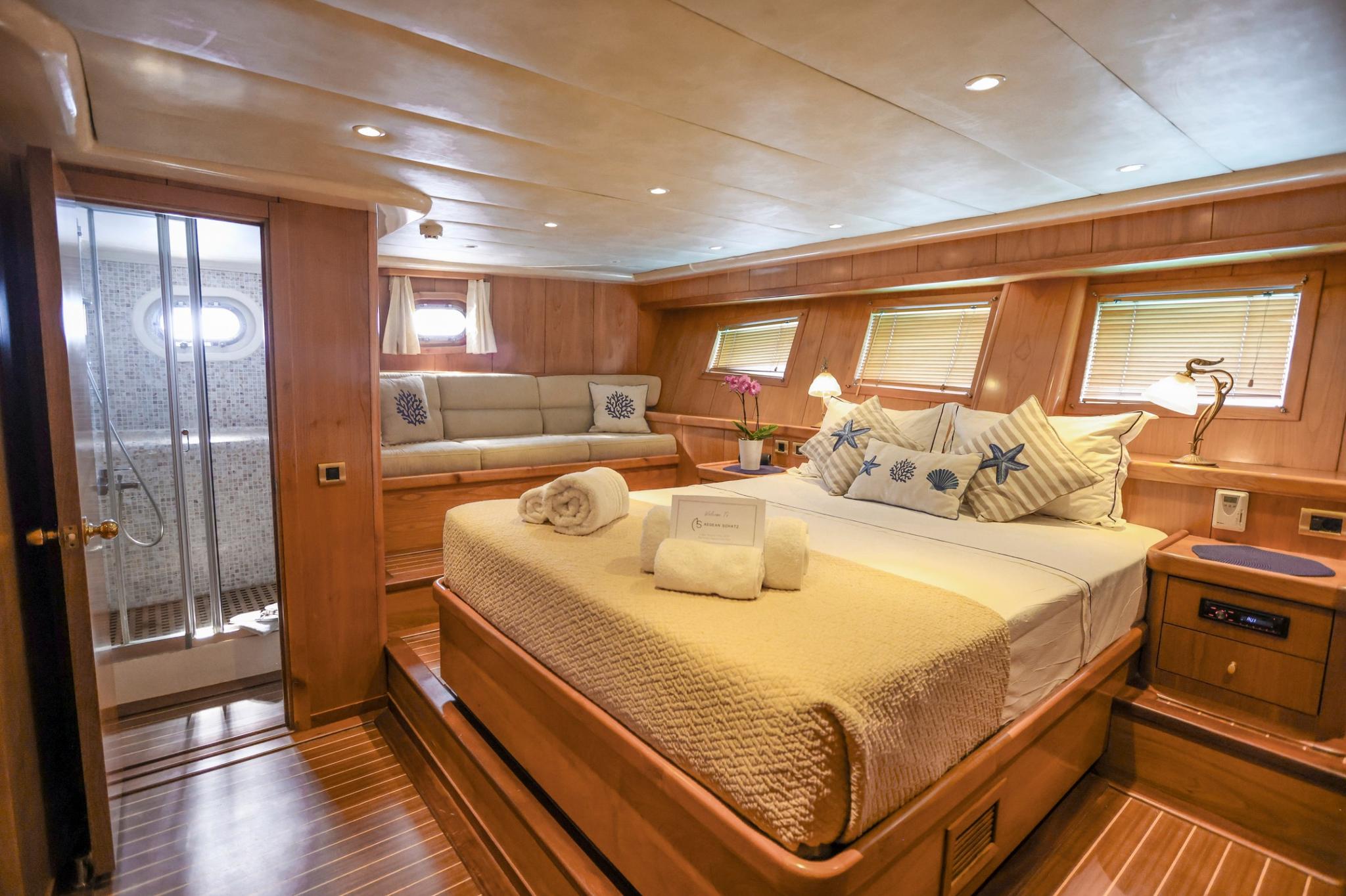 Luxury yacht master cabin featuring king bed, built-in seating, wood paneling and en-suite bathroom