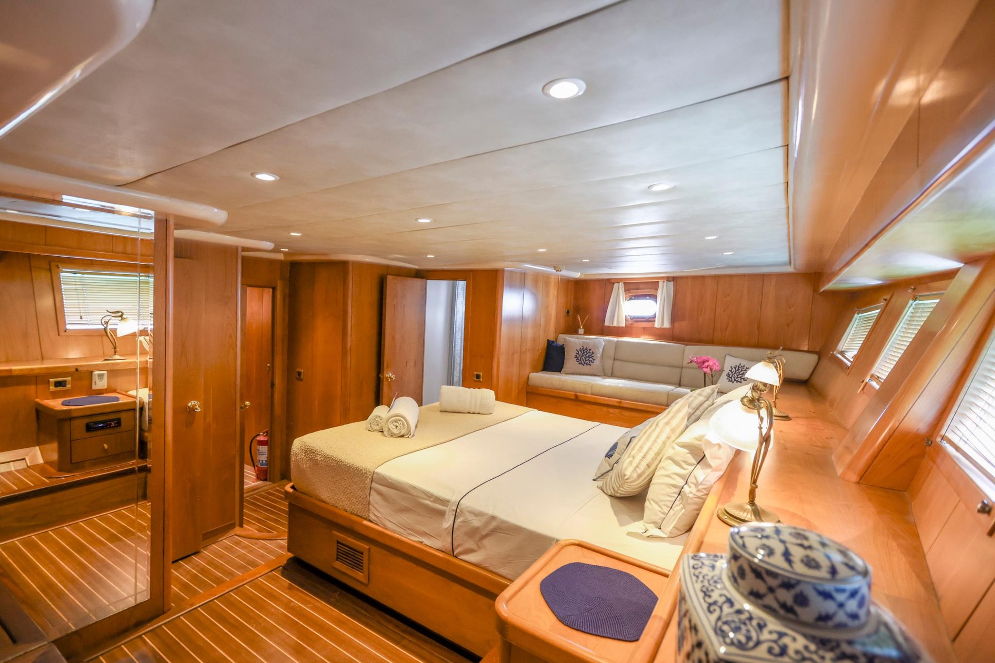 luxury yacht master cabin featuring double bed, built-in seating, wooden paneling and multiple windows