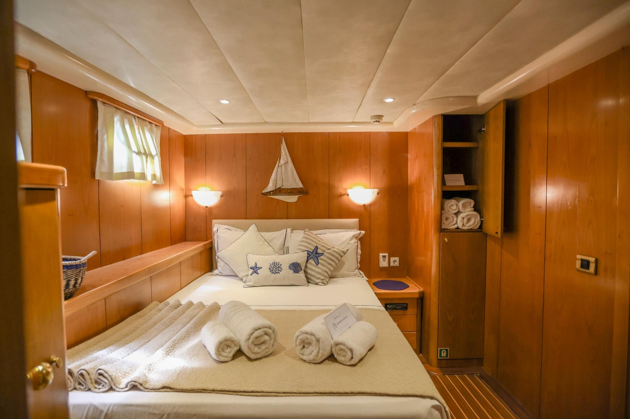 yacht guest cabin featuring double bed with nautical pillows and rich wood paneling