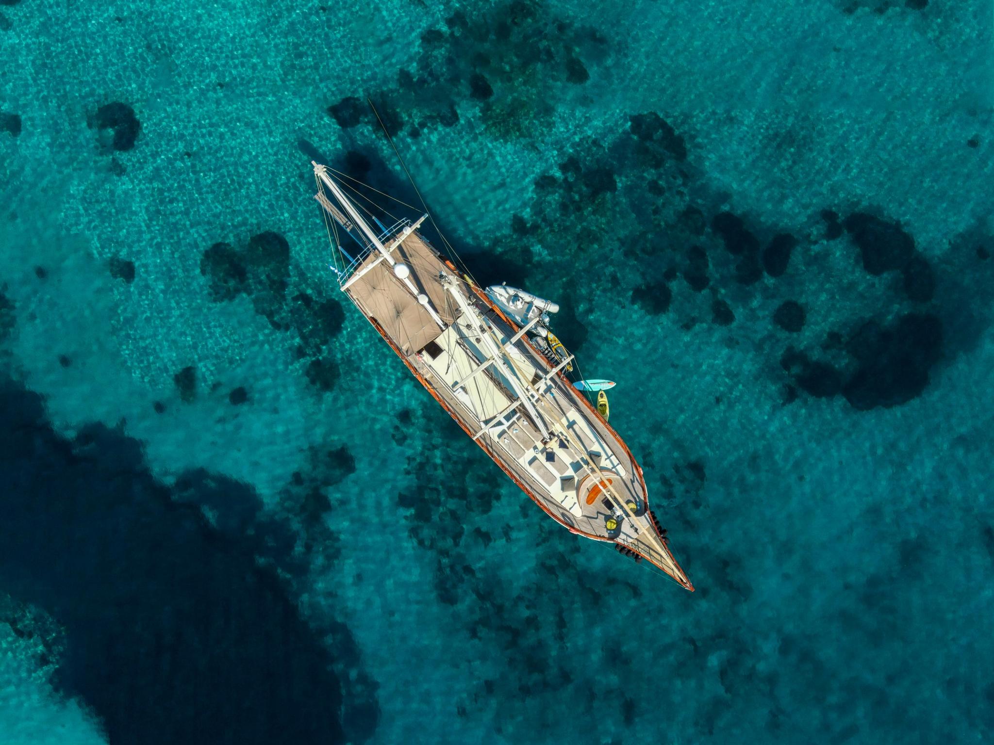 aerial view of traditional wooden gulet yacht anchored in crystal clear turquoise waters
