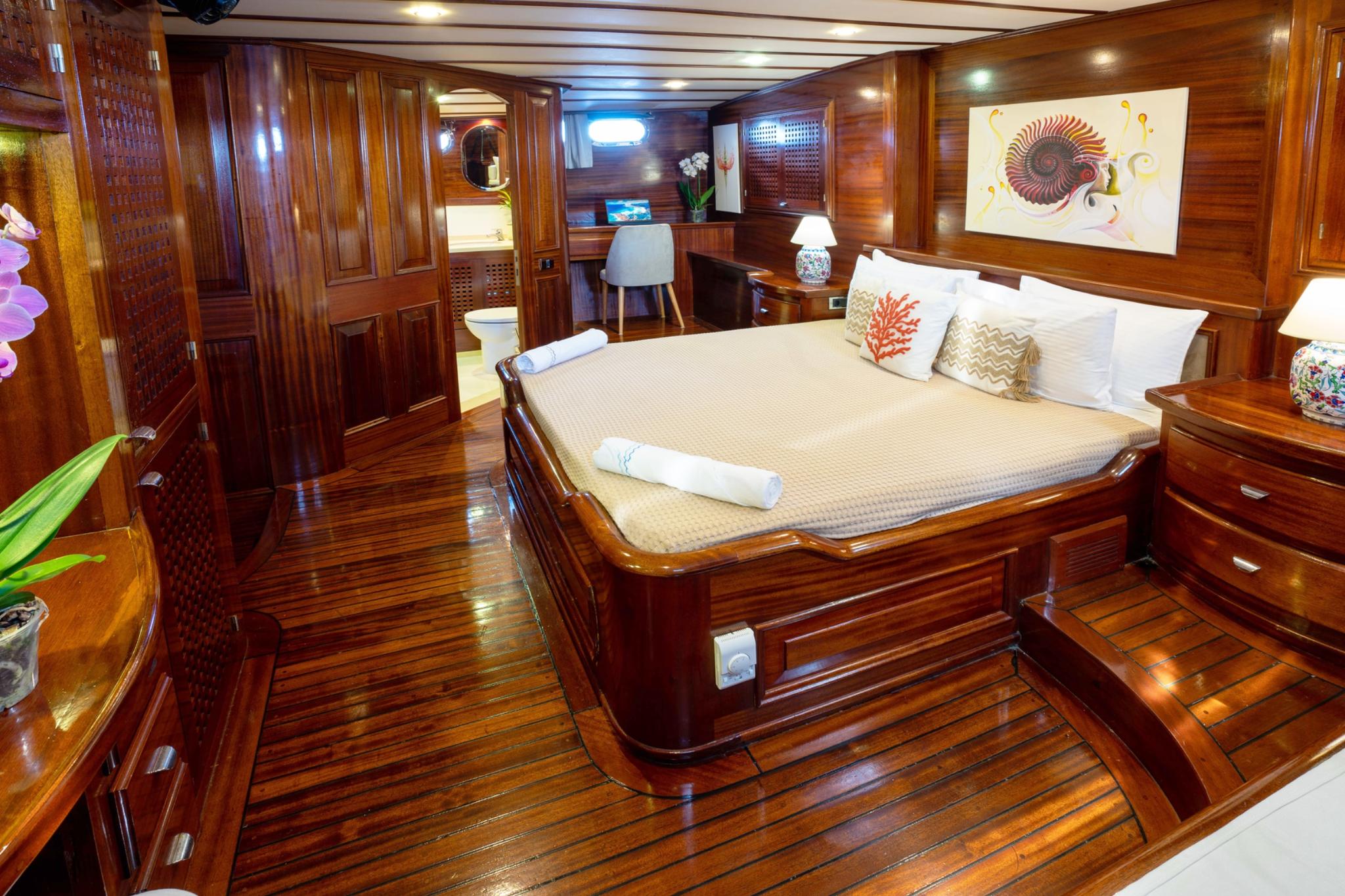 Luxury yacht master cabin featuring king size bed with cream bedding and decorative pillows