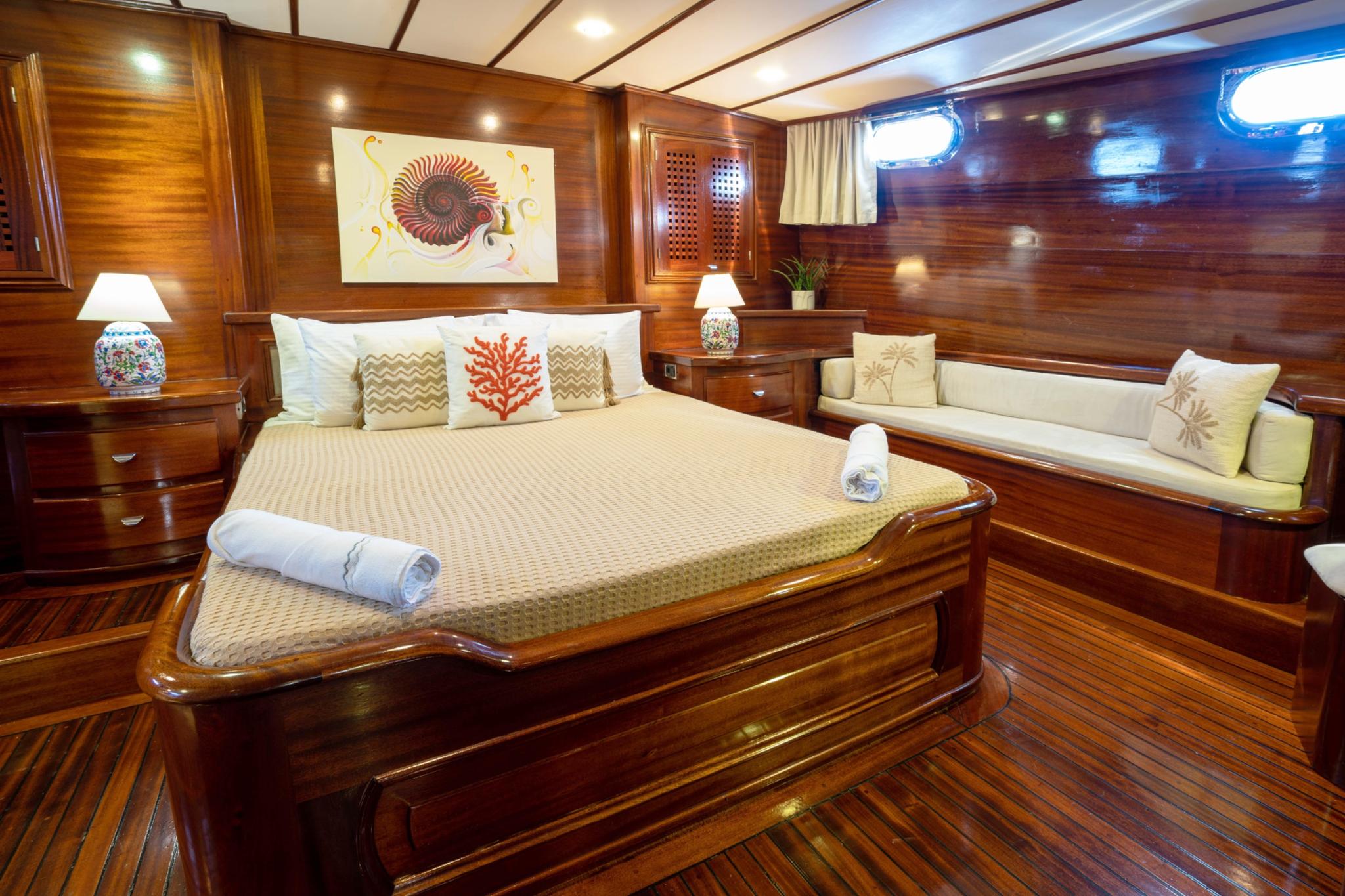 yacht guest cabin featuring double bed with coral decorative pillow and built-in seating