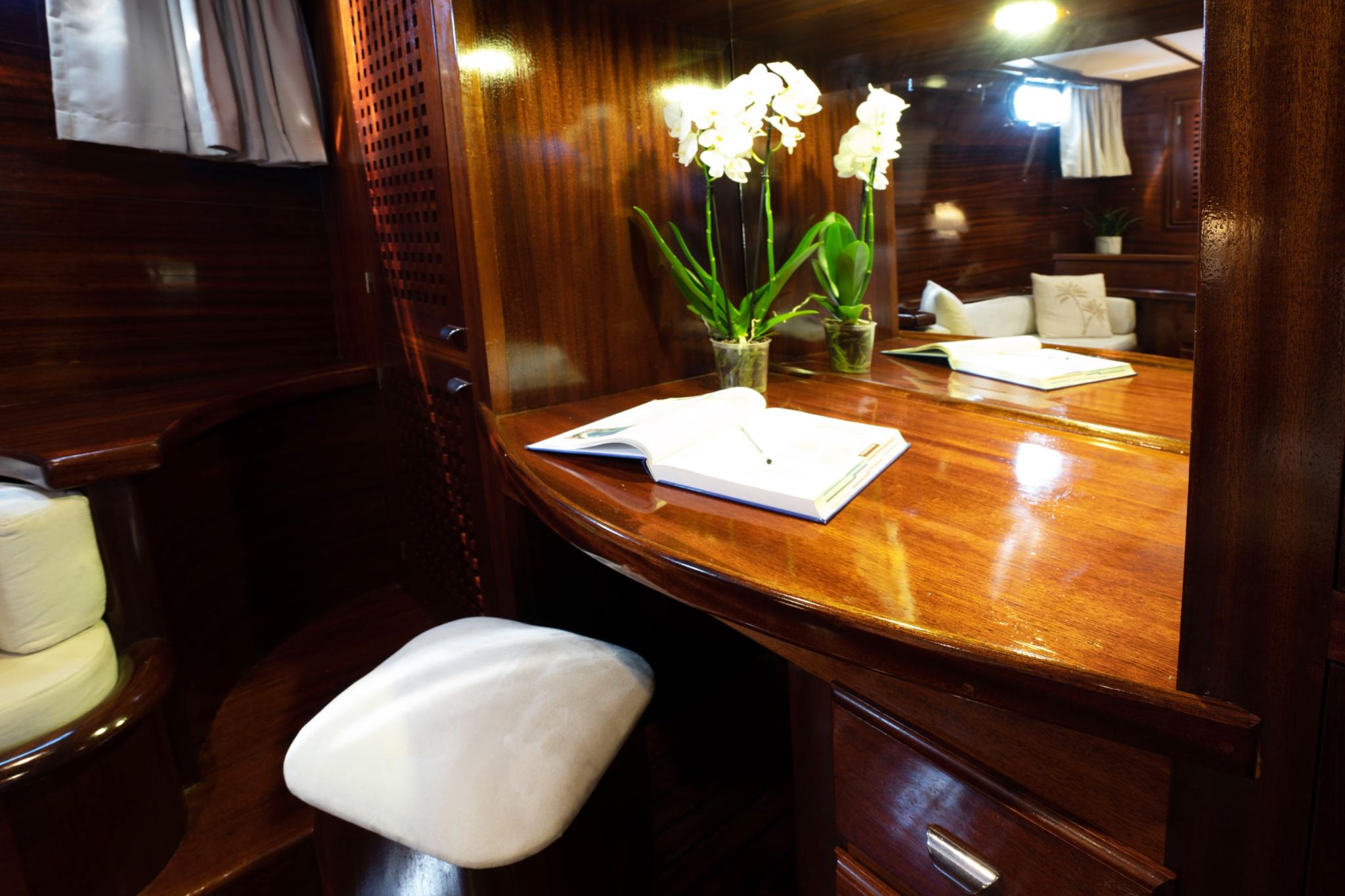 yacht office area with polished wooden desk, white orchids, and cream seating