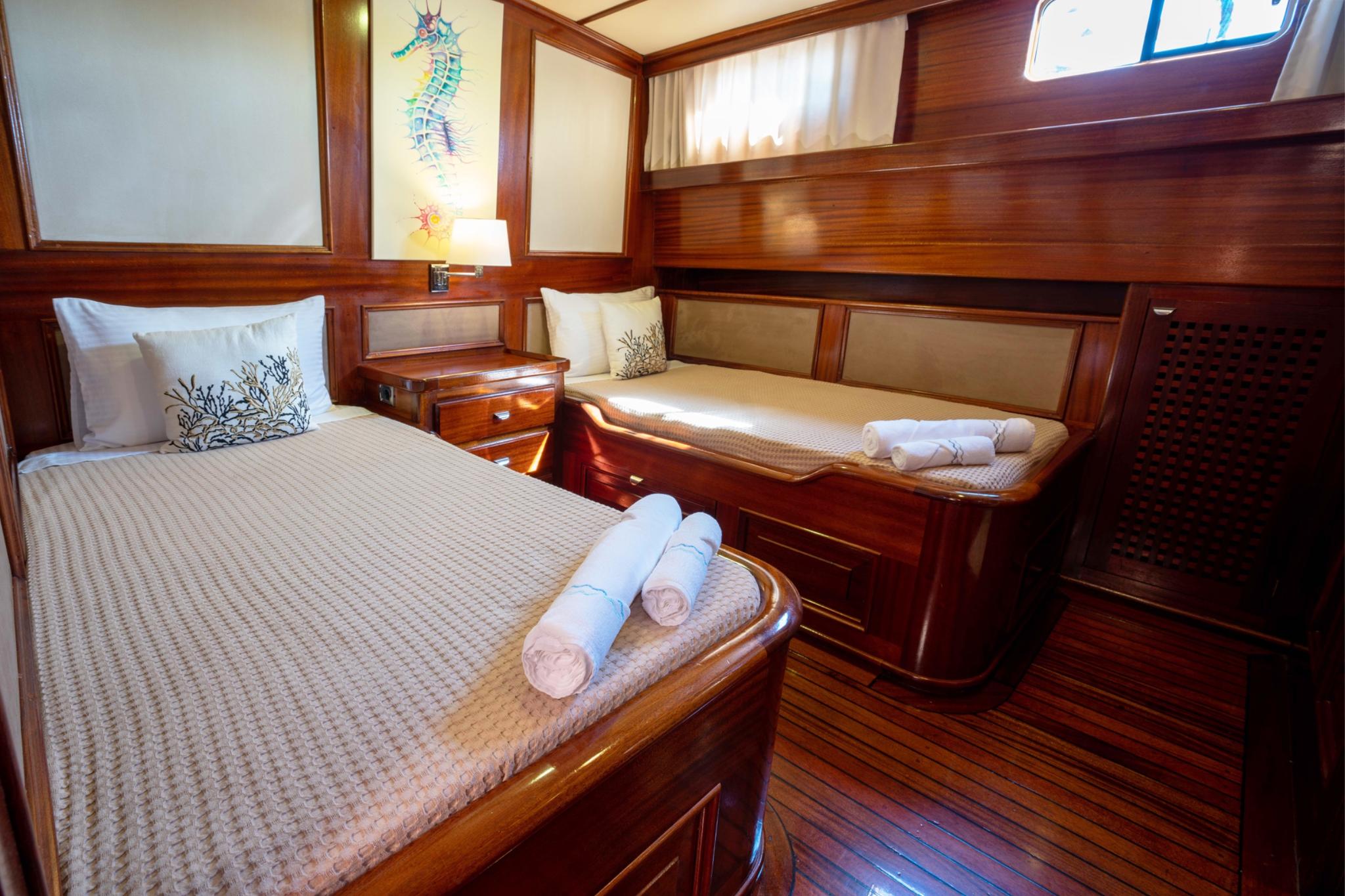 yacht guest cabin featuring twin beds with coral-patterned pillows and seahorse artwork