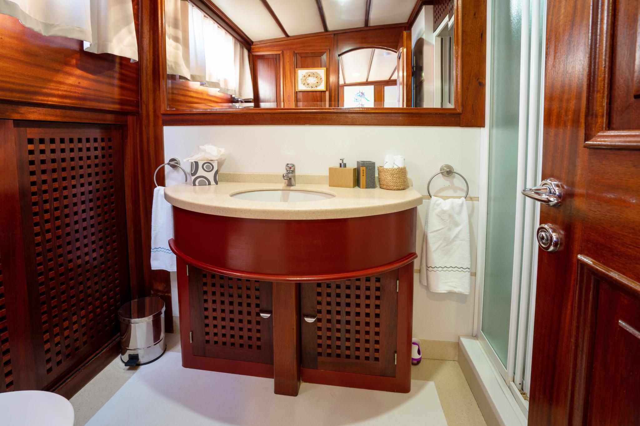 yacht bathroom featuring curved wooden vanity with cream marble countertop and latticed cabinet doors