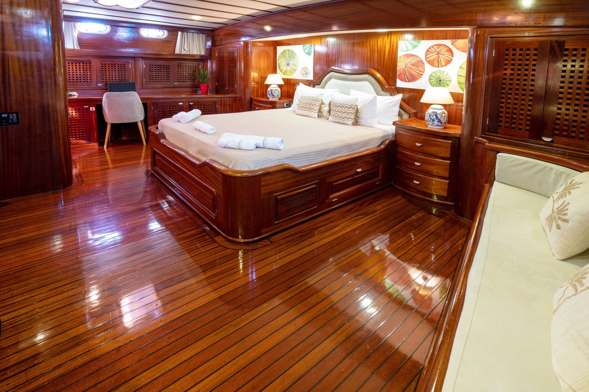 luxury yacht master cabin featuring king bed with white linens and rich mahogany wood finishes