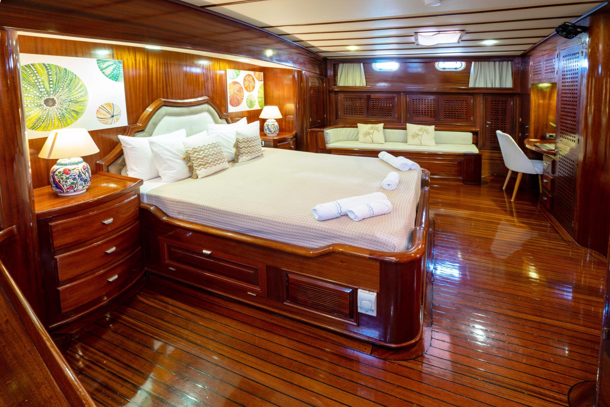 luxurious master cabin featuring king bed, built-in seating, rich wood paneling and portholes