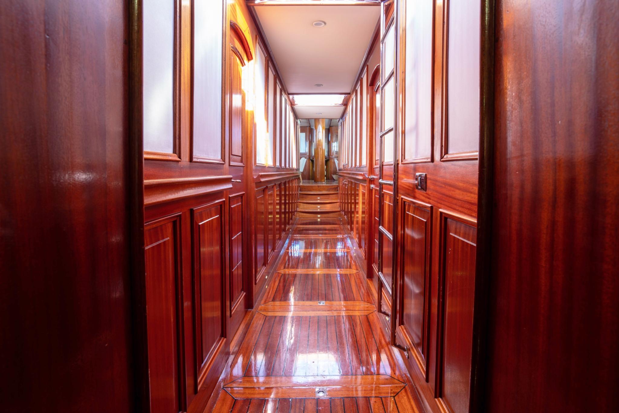 yacht interior hallway with rich wood paneling leading to guest cabins