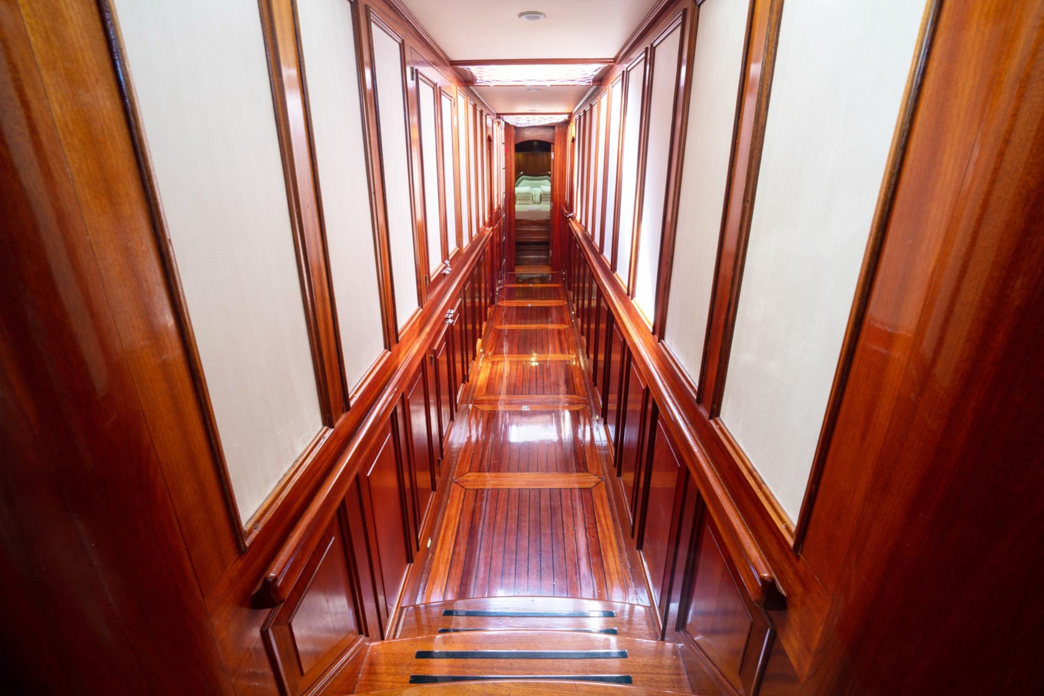 polished wood staircase descending to yacht cabin corridor with white walls