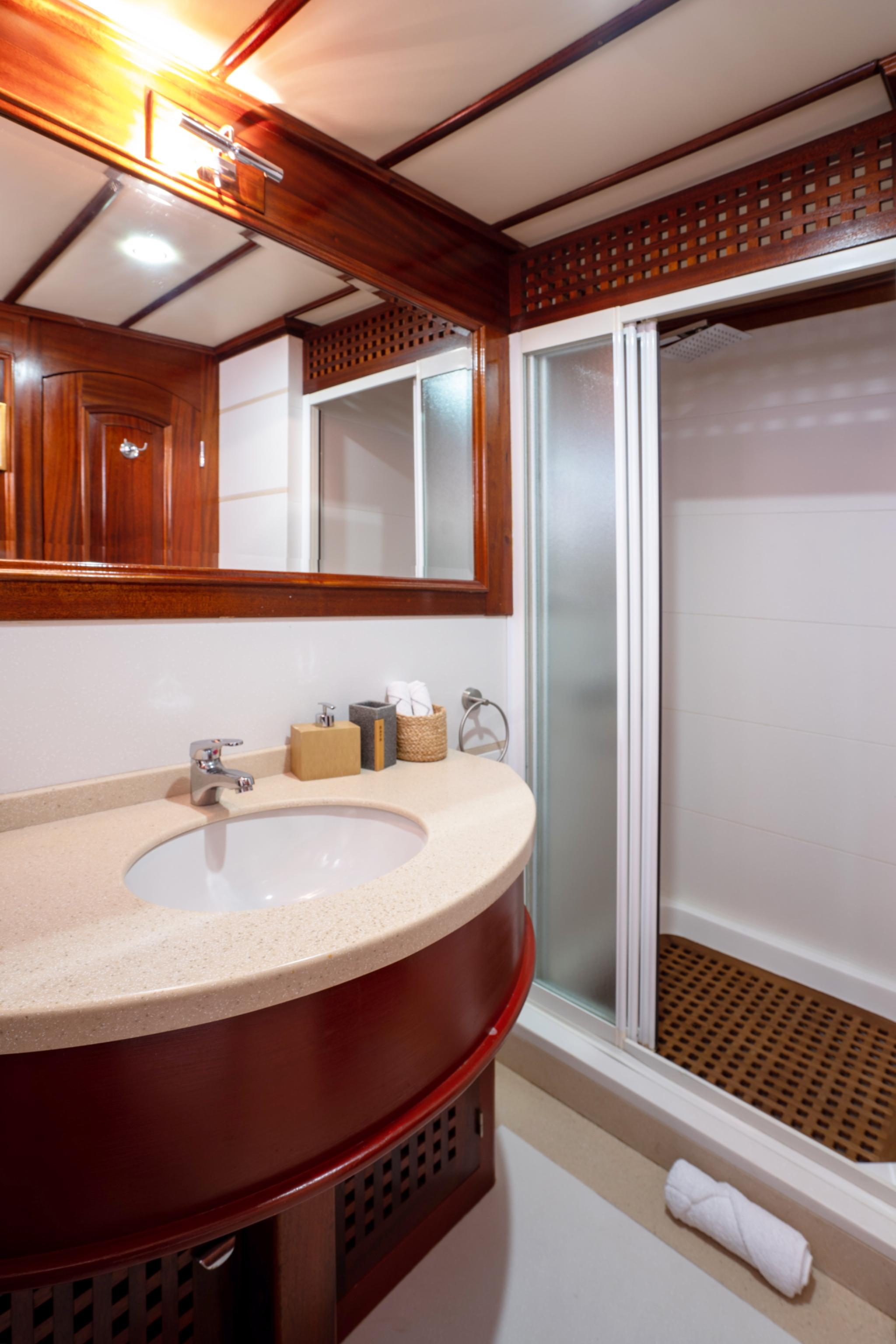 yacht bathroom featuring curved stone vanity with undermount sink and frosted glass shower door