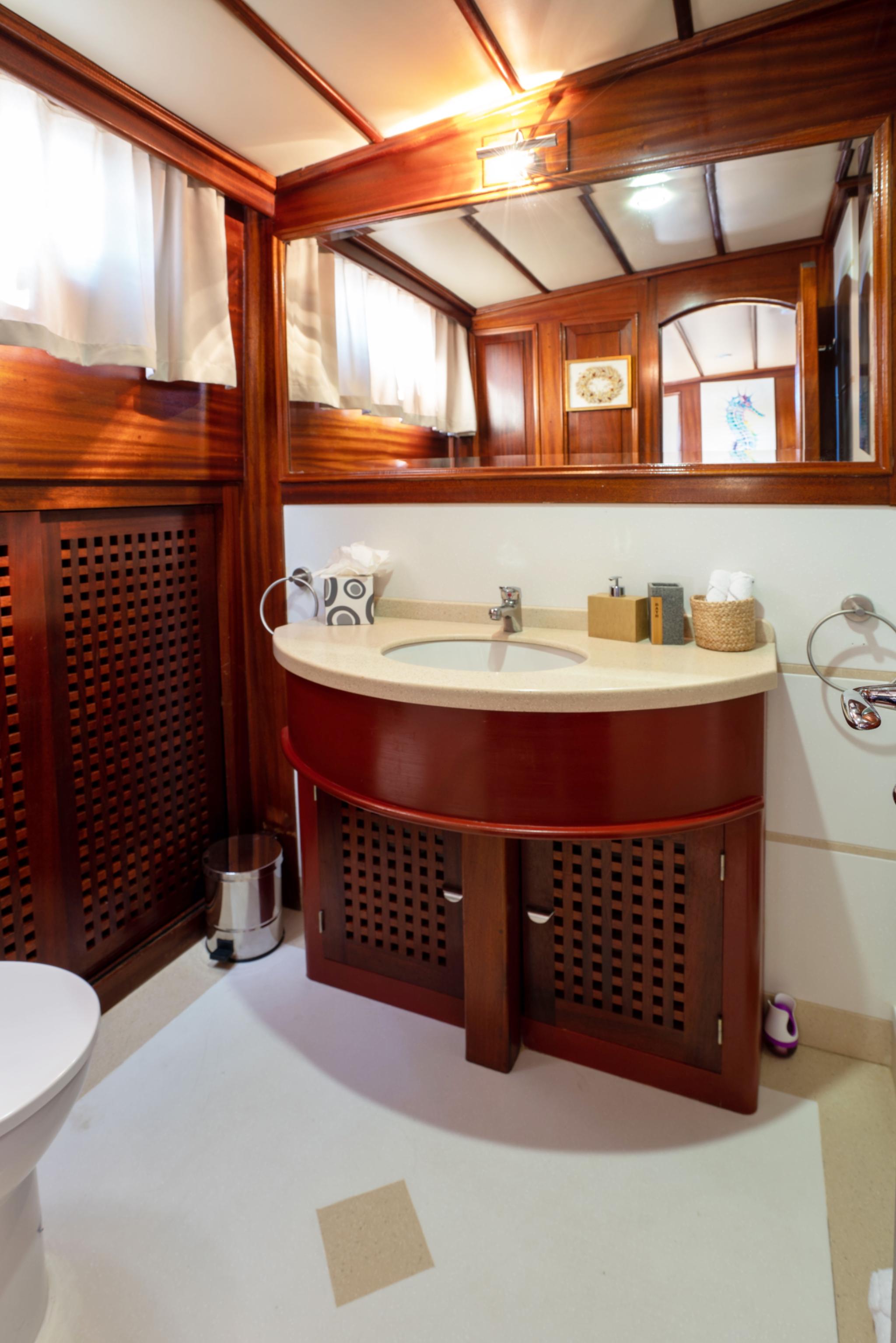 yacht bathroom featuring curved wooden vanity with white countertop and oval mirror