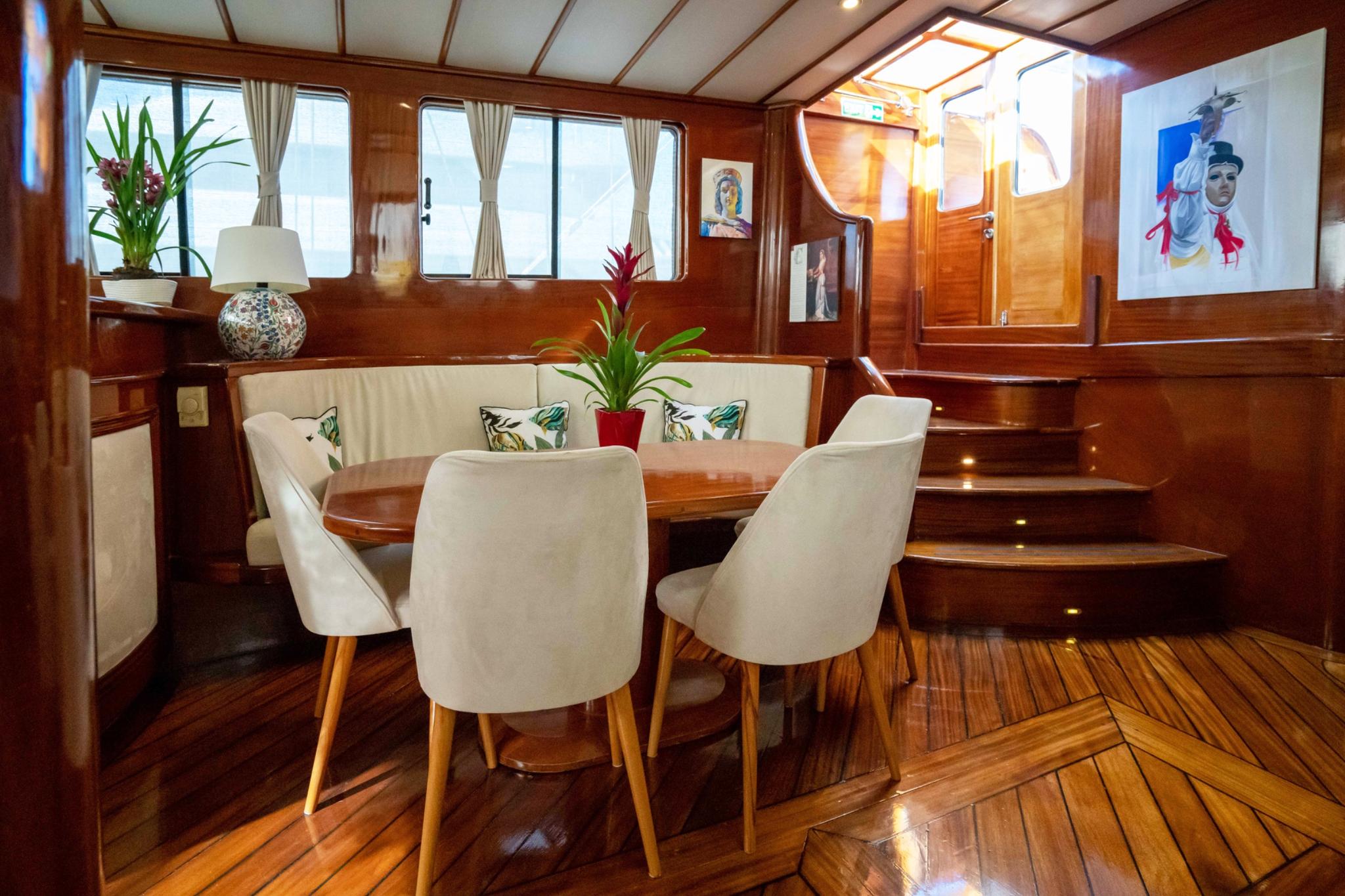 yacht salon interior with built-in banquette seating, dining table, and modern chairs