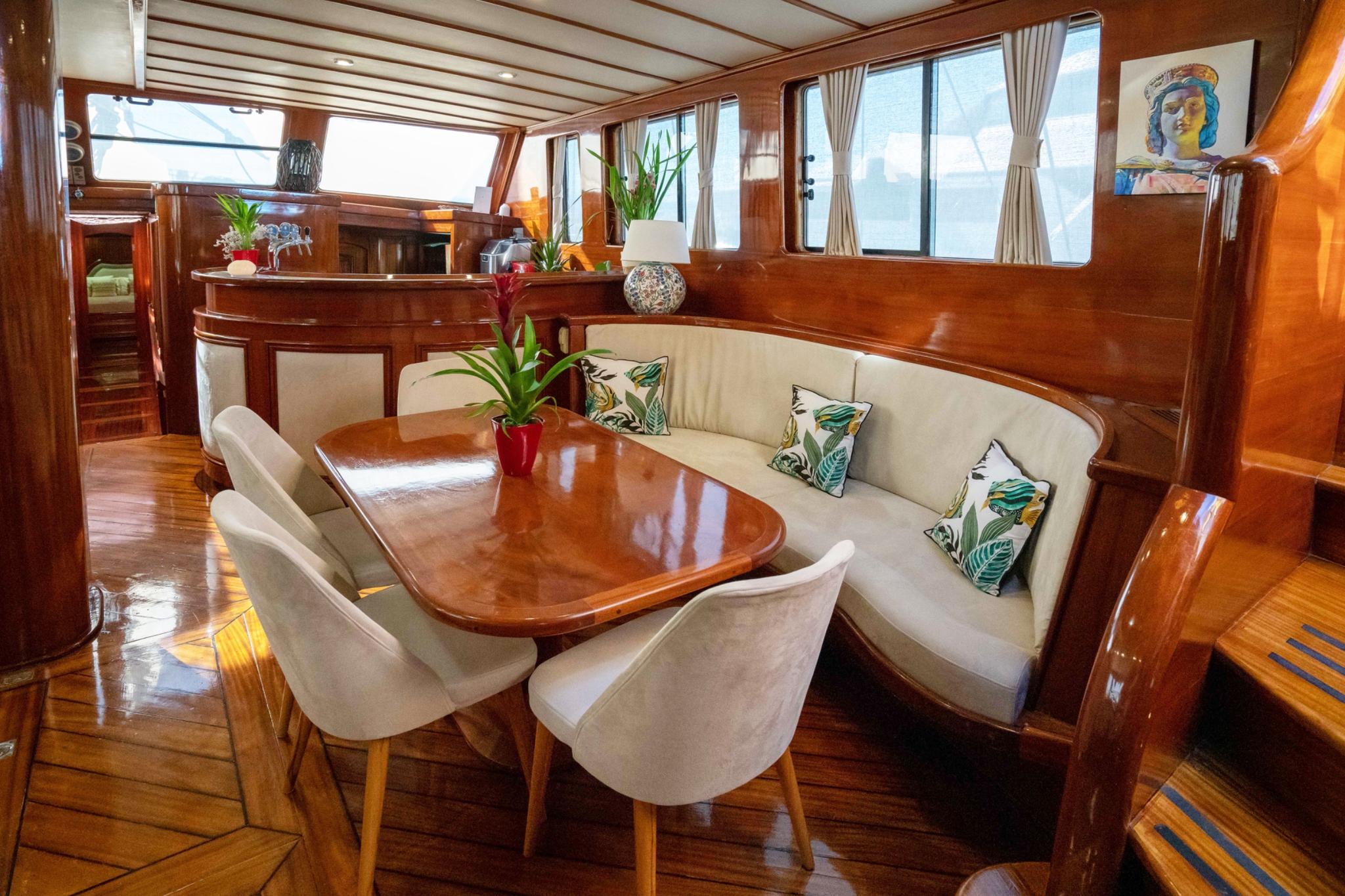yacht main salon interior with curved cream banquette, oval dining table, and large windows