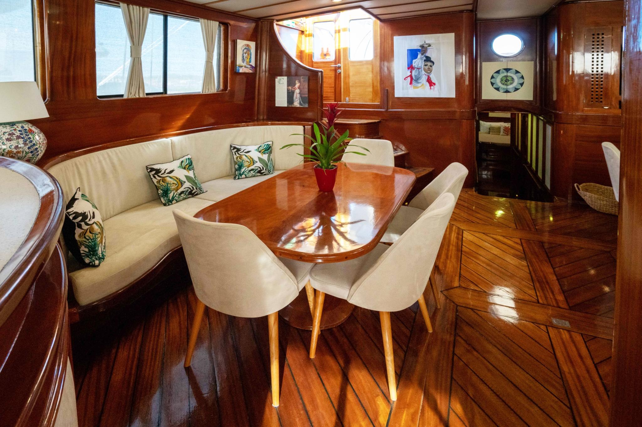 yacht salon interior with curved banquette seating, oval dining table, and upholstered chairs