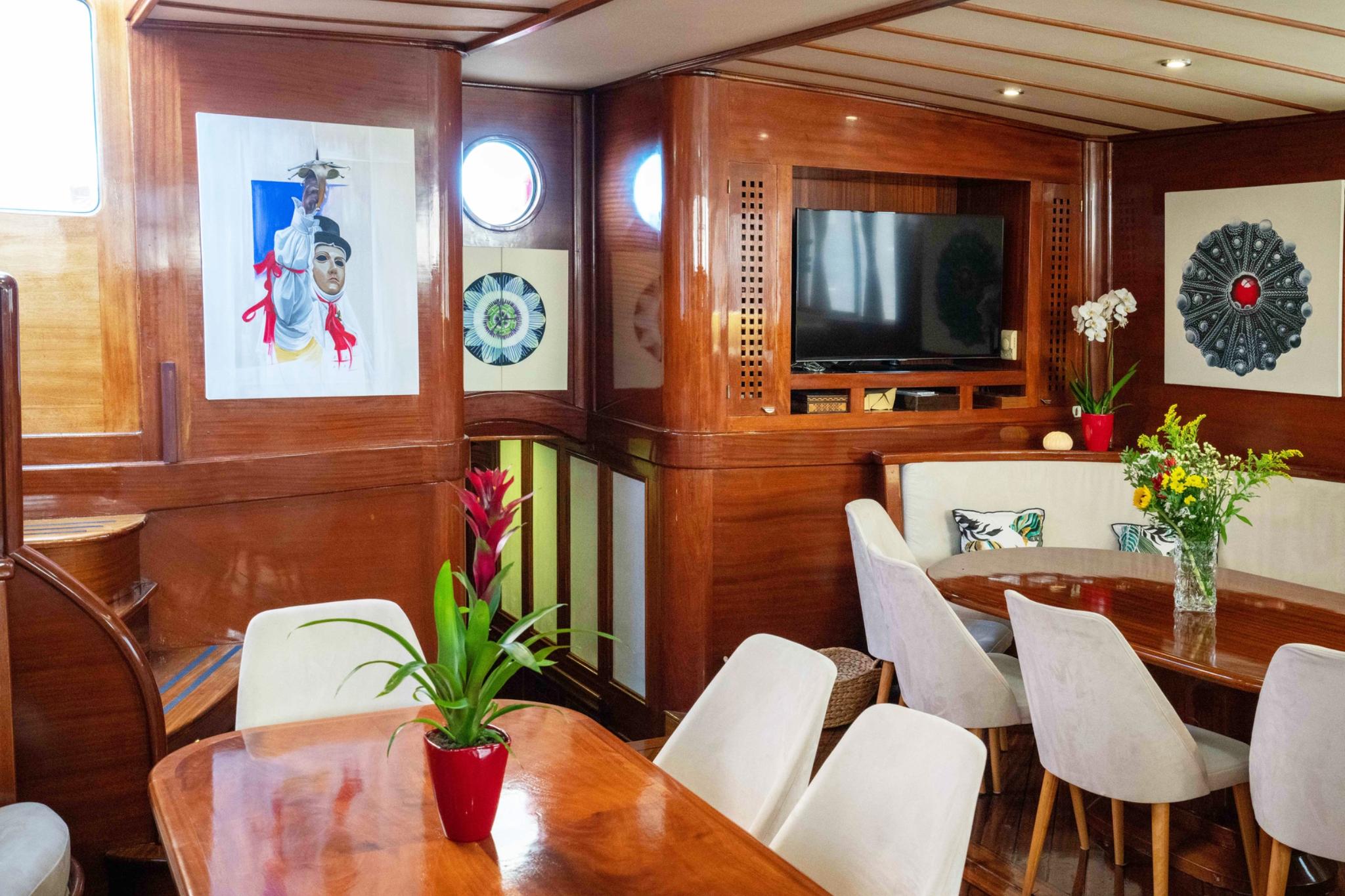 yacht salon interior with dining table, white chairs, flat screen TV and decorative artwork