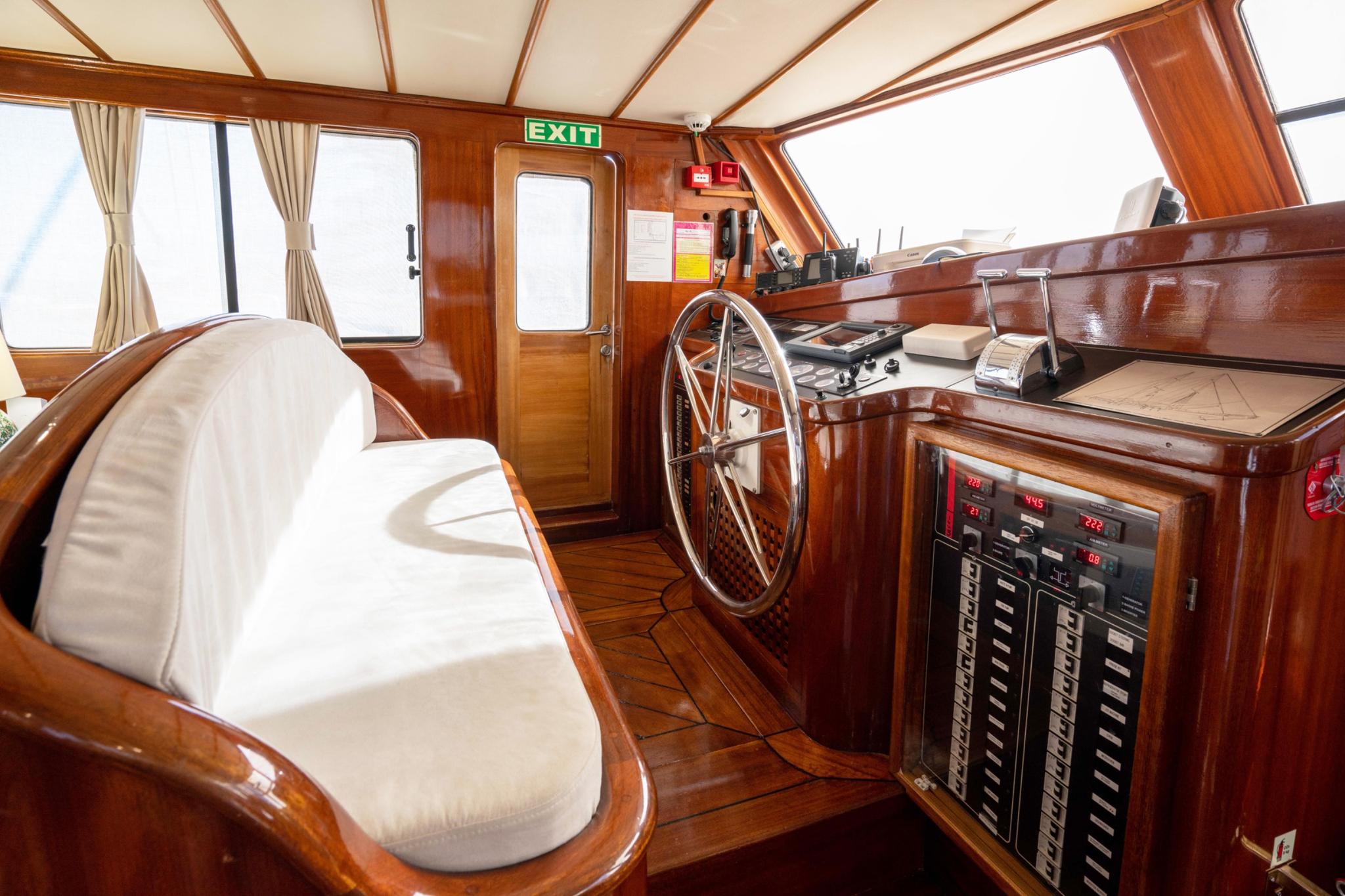 yacht wheelhouse interior showing helm wheel, navigation instruments, captain's chair and windows
