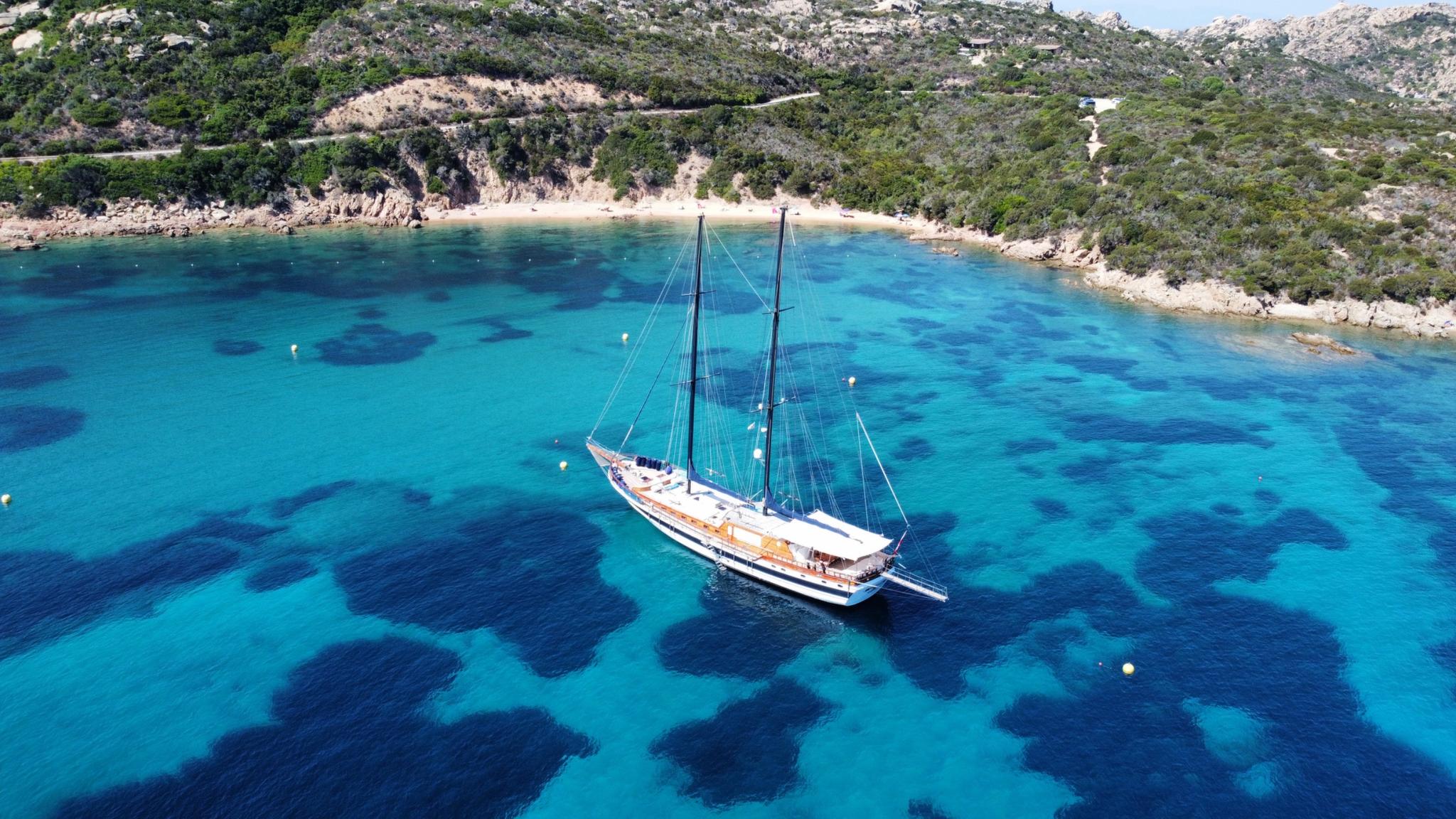 aerial view of traditional wooden gulet yacht anchored in crystal clear turquoise Mediterranean bay