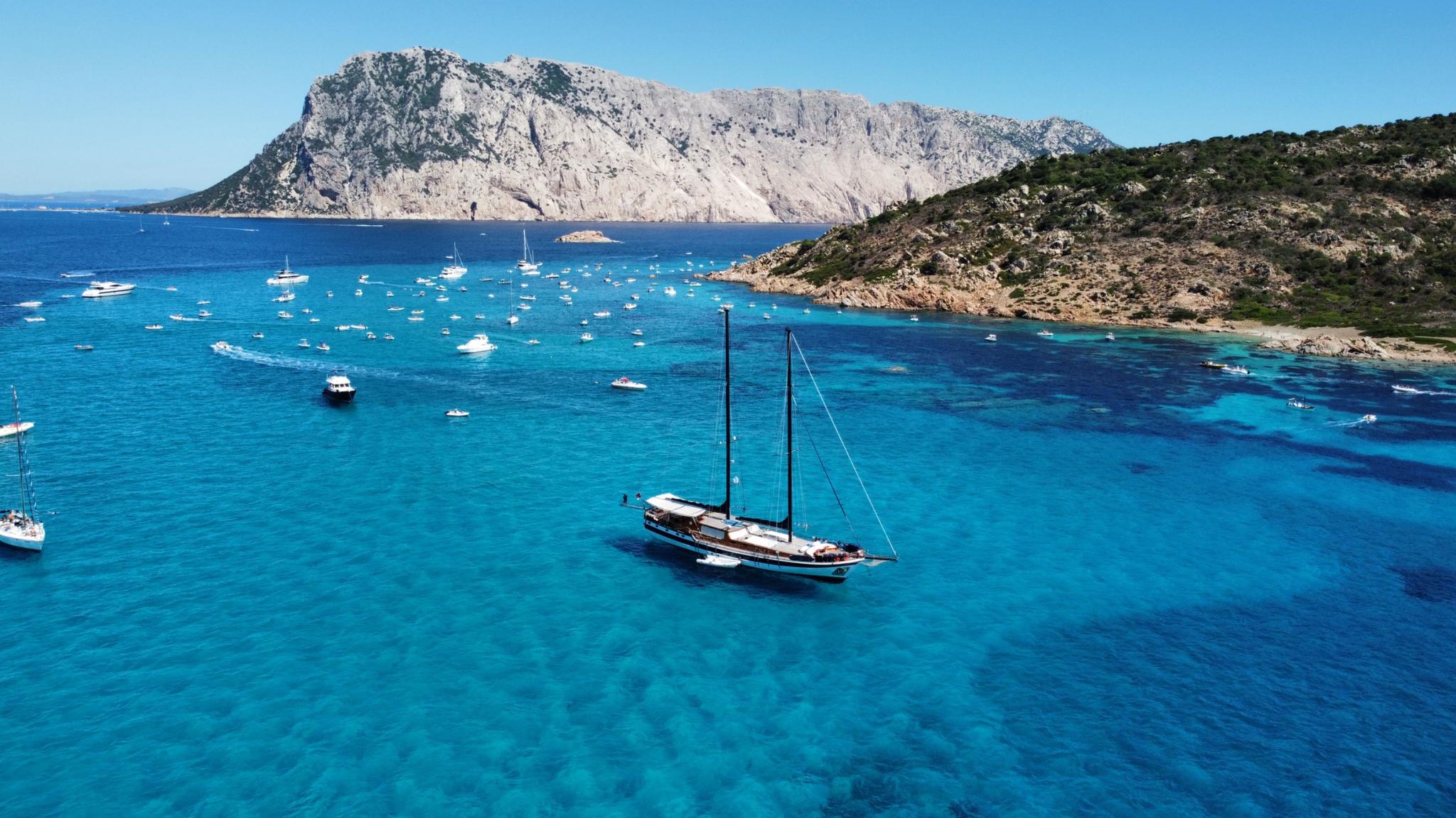 aerial view of traditional wooden gulet anchored in crystal clear turquoise Mediterranean bay
