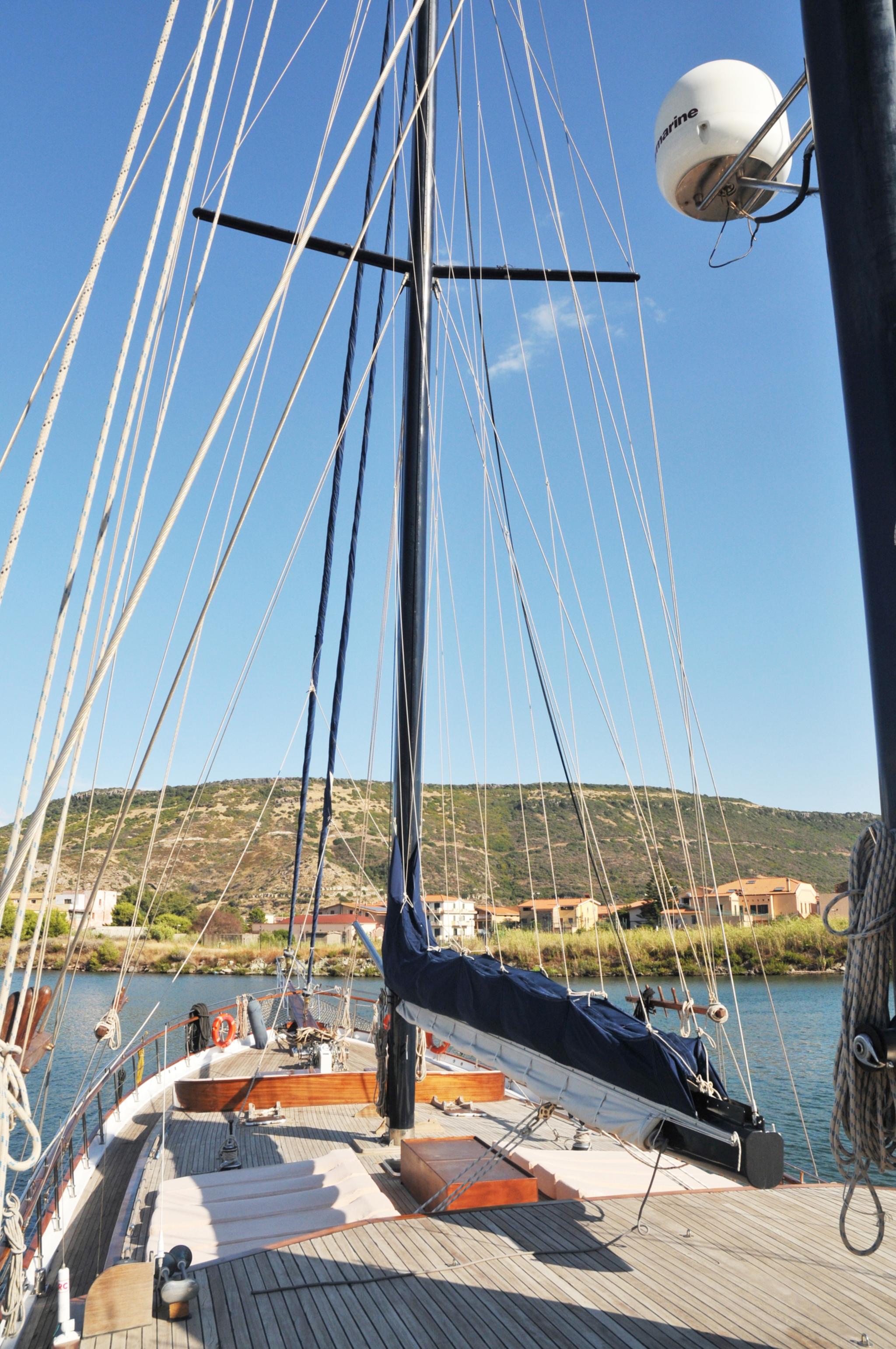 yacht deck showing mast rigging furled sails and coastal backdrop