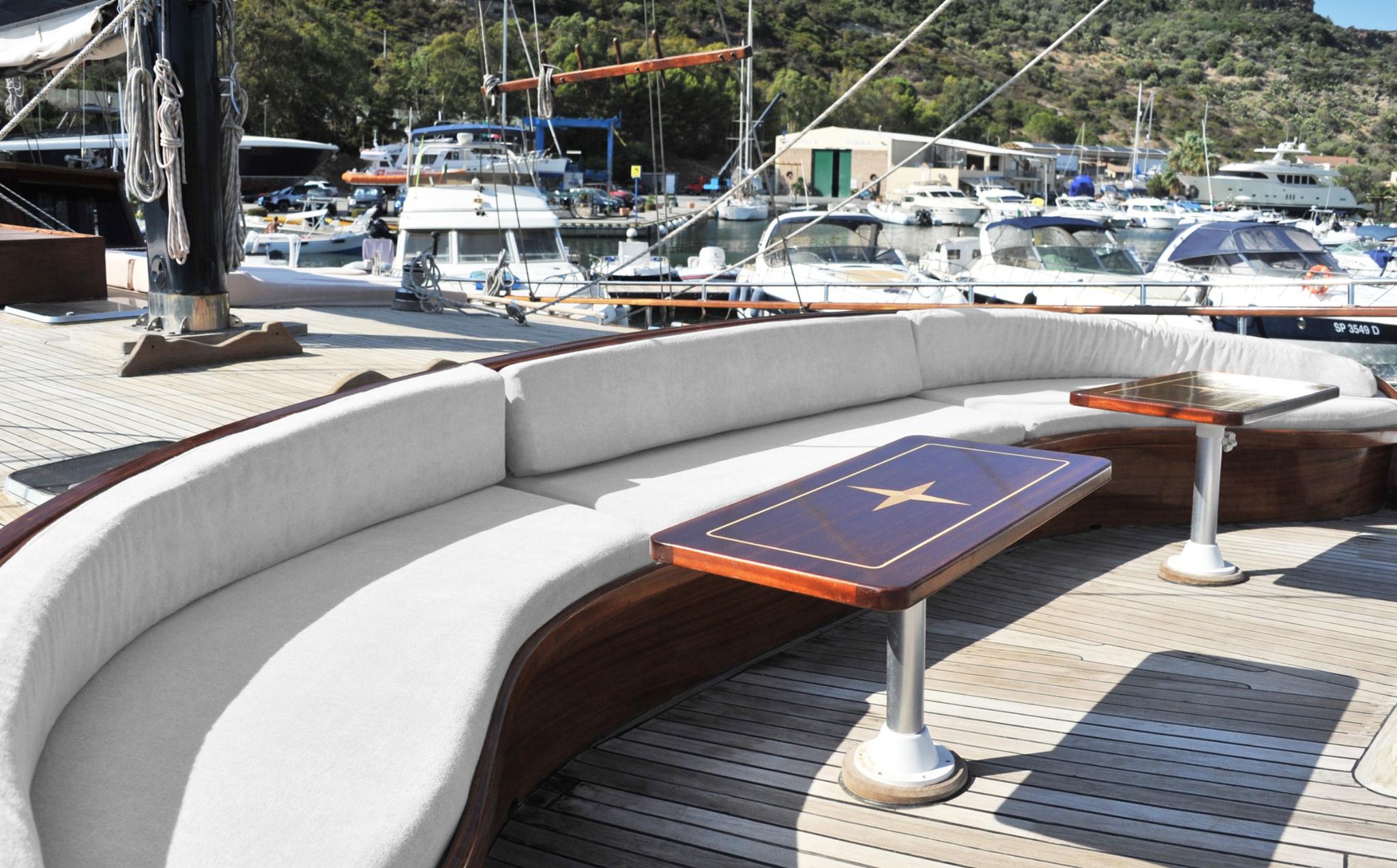 curved outdoor seating with blue game table on yacht deck in marina