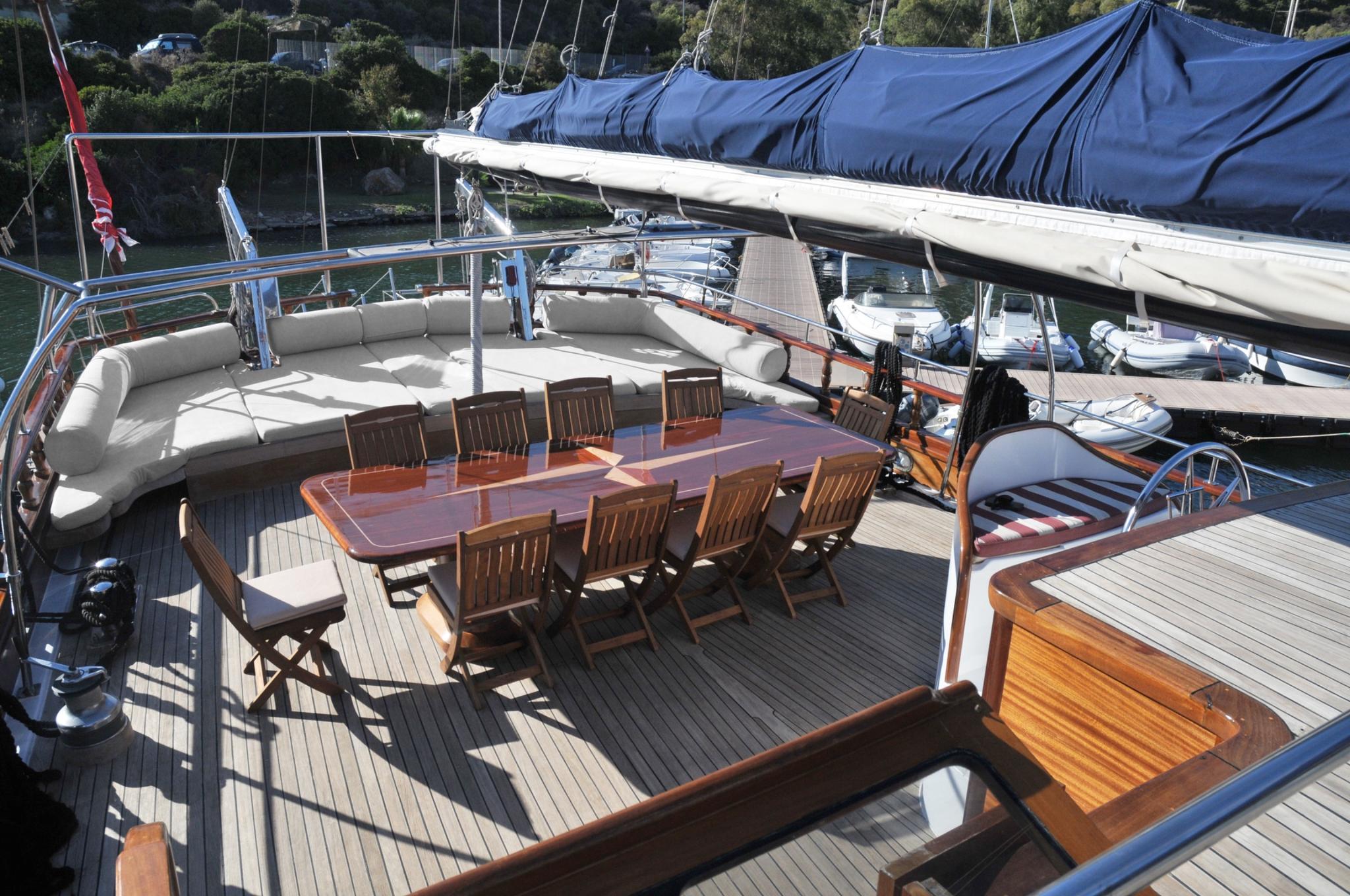 gulet aft deck with teak dining table, wooden chairs and built-in seating area
