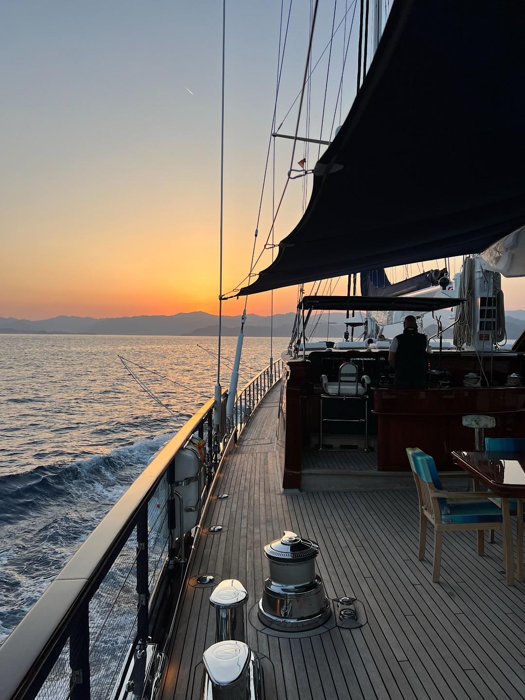 gulet deck with sailing rigging, winches and teak decking at sunset