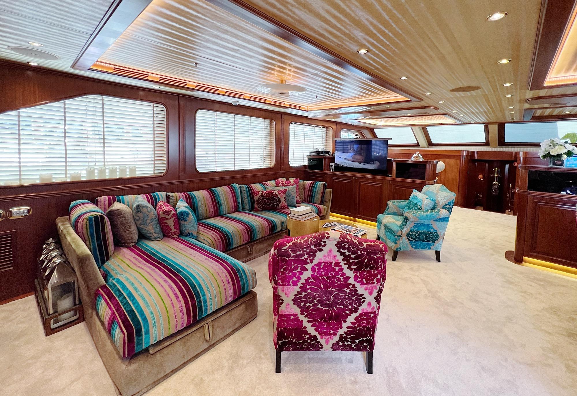 yacht cinema room with wall-mounted screen and vibrant striped sofas and floral chairs