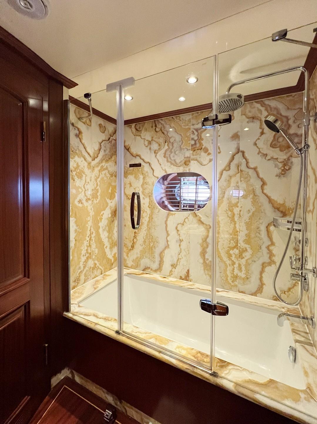 luxury yacht bathroom featuring marble-walled shower with glass doors and rainfall showerhead