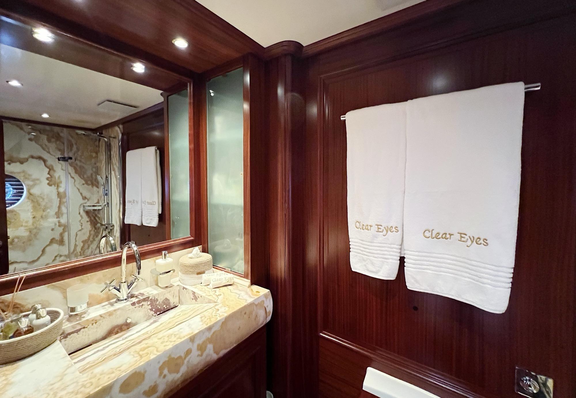 yacht bathroom featuring marble vanity counter, chrome faucet, mirror and dark wood paneling