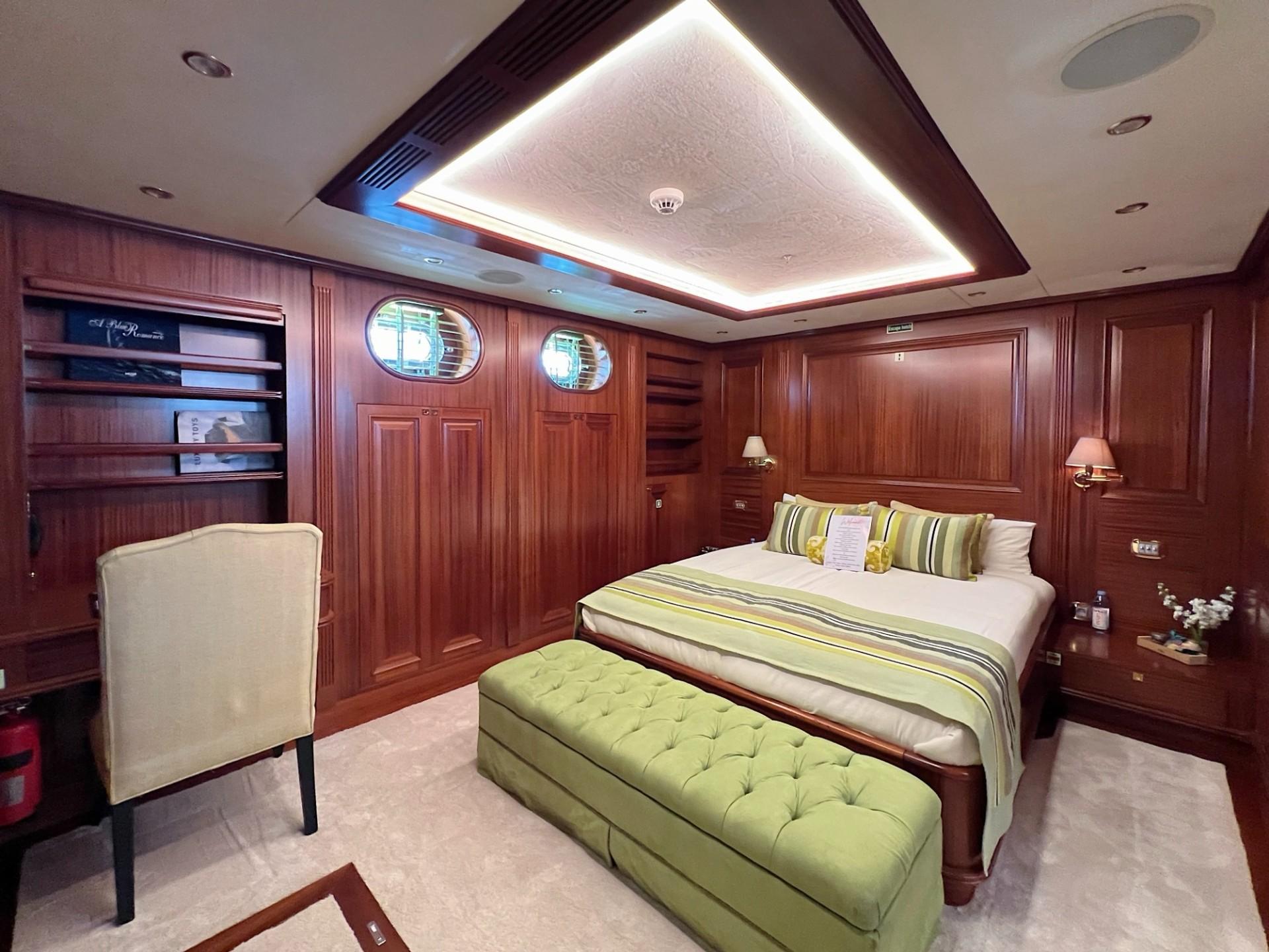 luxurious master cabin featuring double bed with green striped linens and mahogany wood paneling