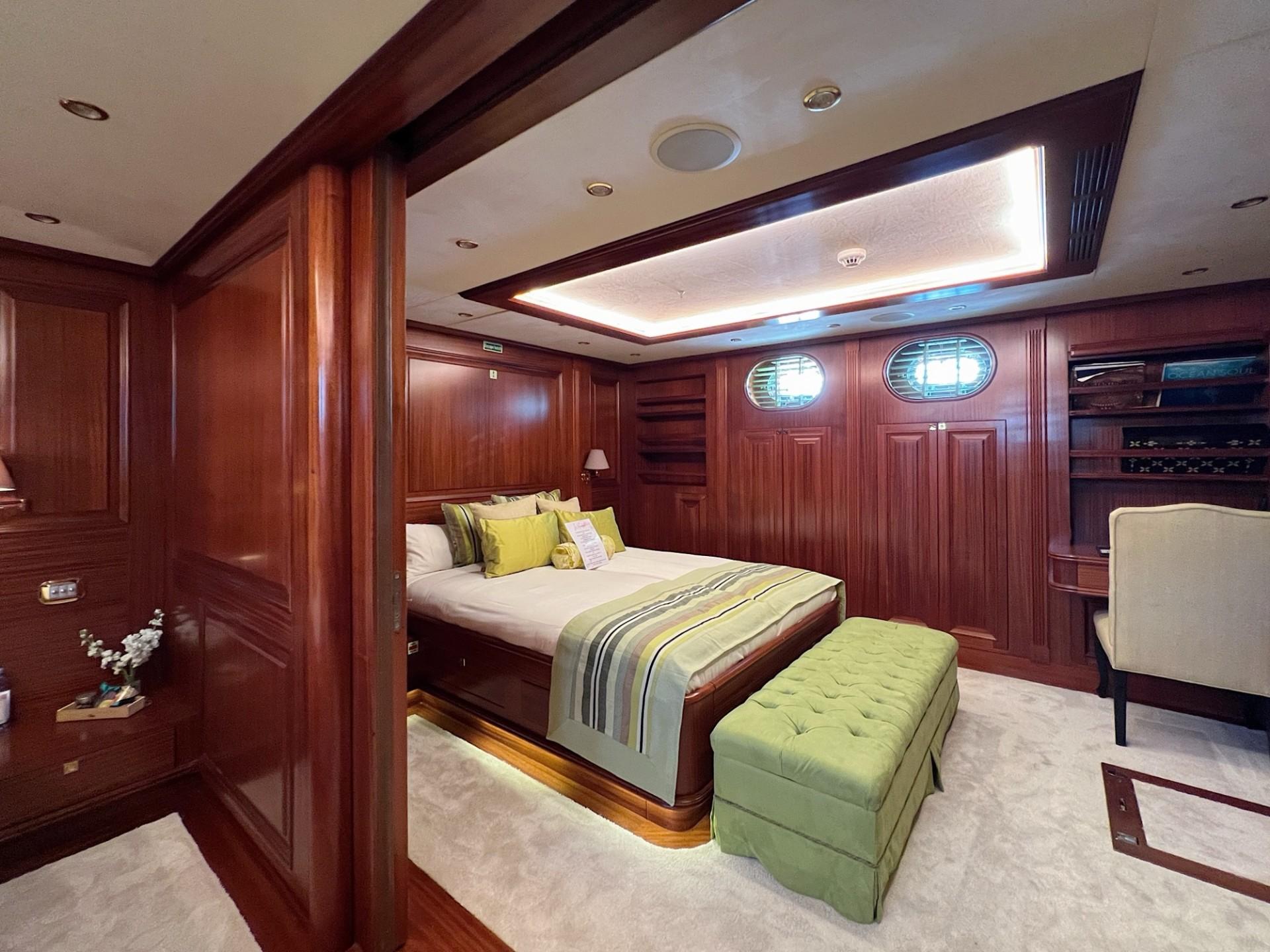 yacht cabin interior featuring double bed with green pillows and rich mahogany paneling
