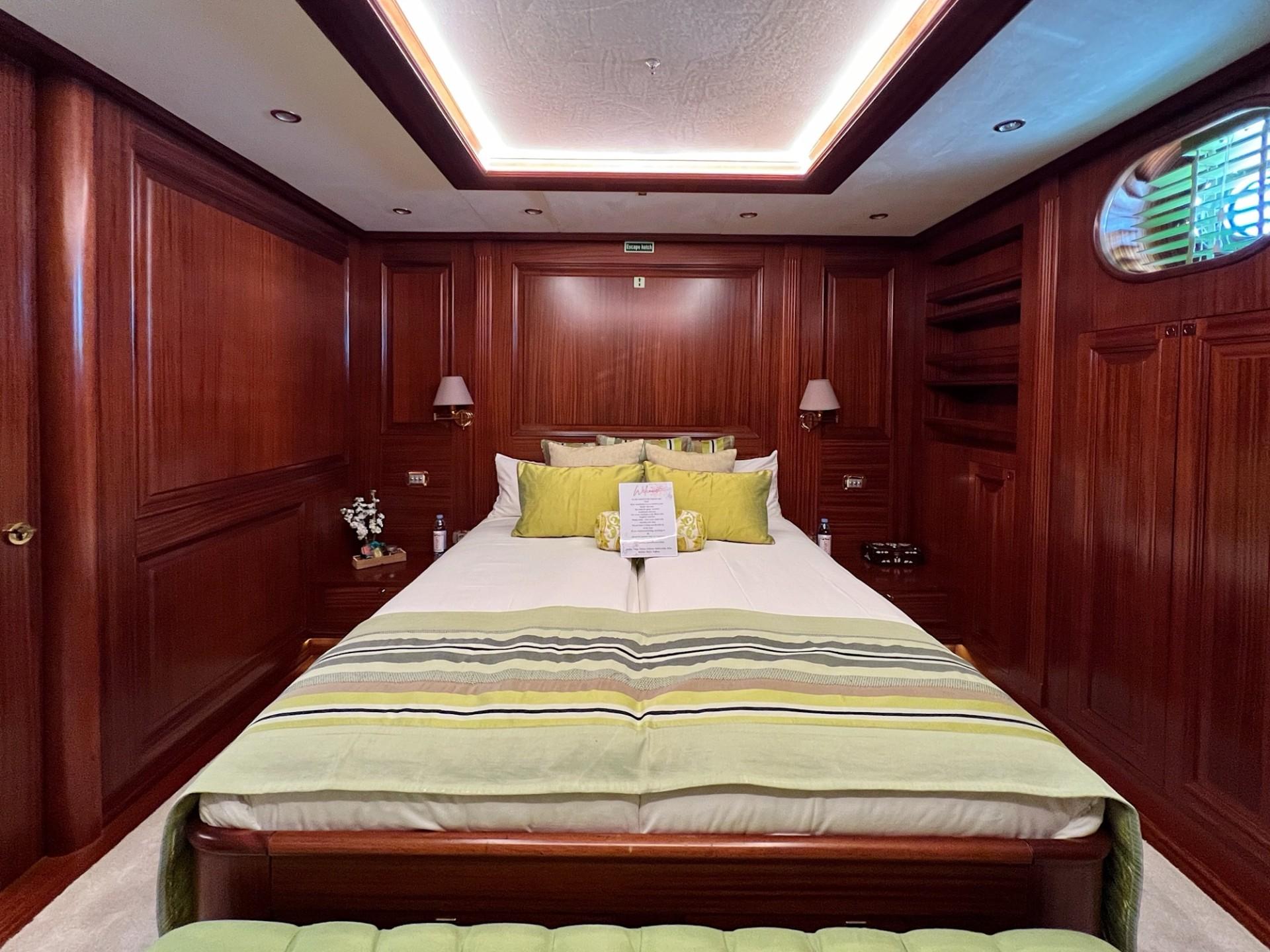 yacht guest cabin with double bed, mahogany wood paneling and bedside reading lamps
