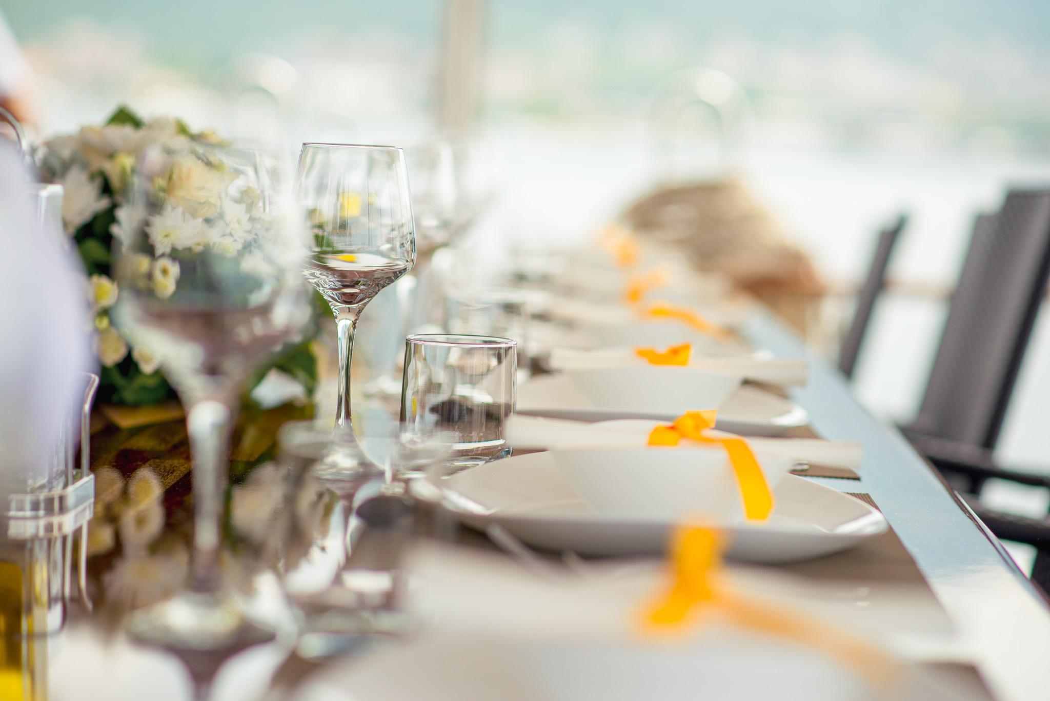 elegantly set outdoor dining table with crystal wine glasses, white floral centrepiece, and yellow ribbon-tied napkins aboard a luxury gulet